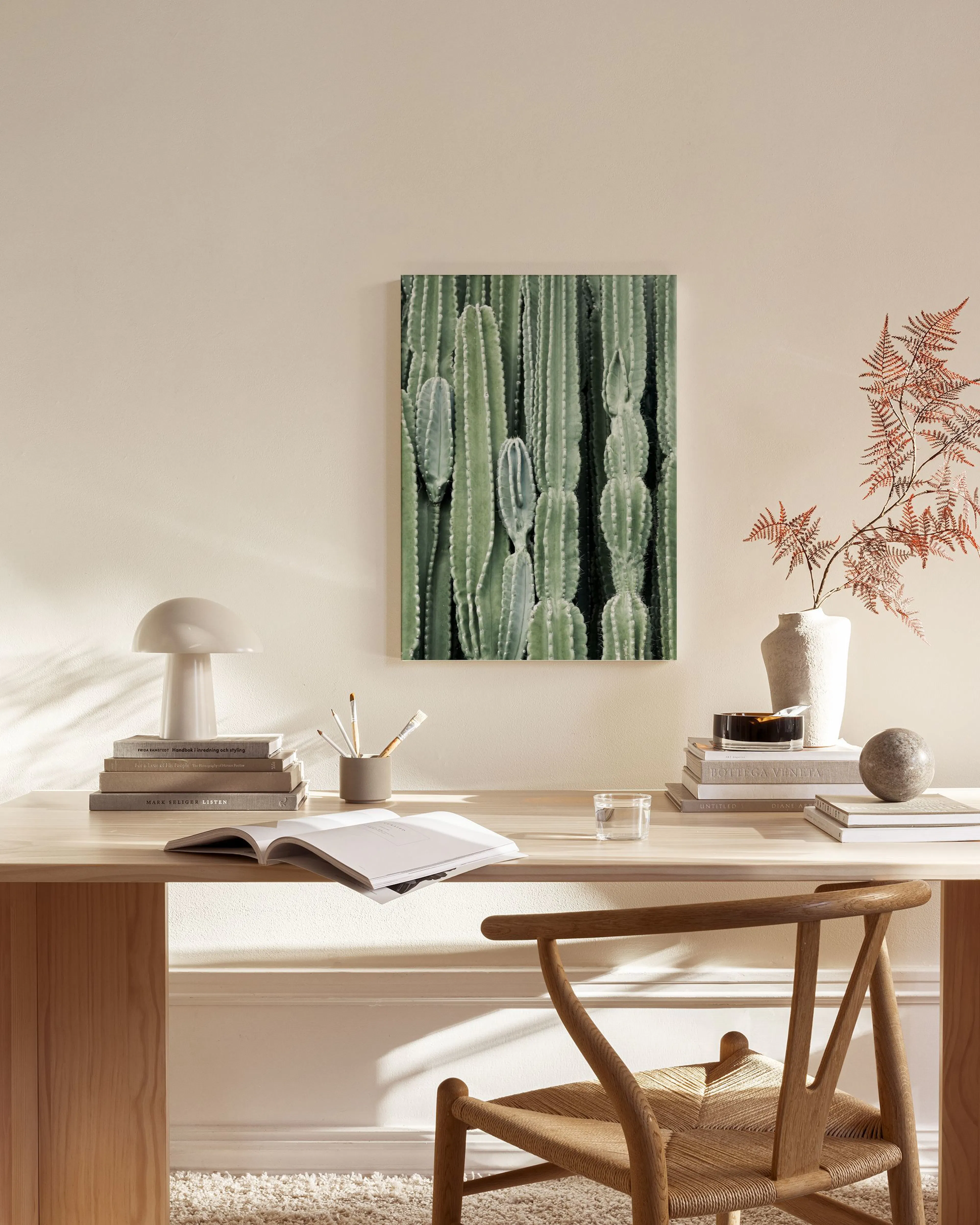 Print of green cacti, displayed above a wooden console table in a minimalist living room.