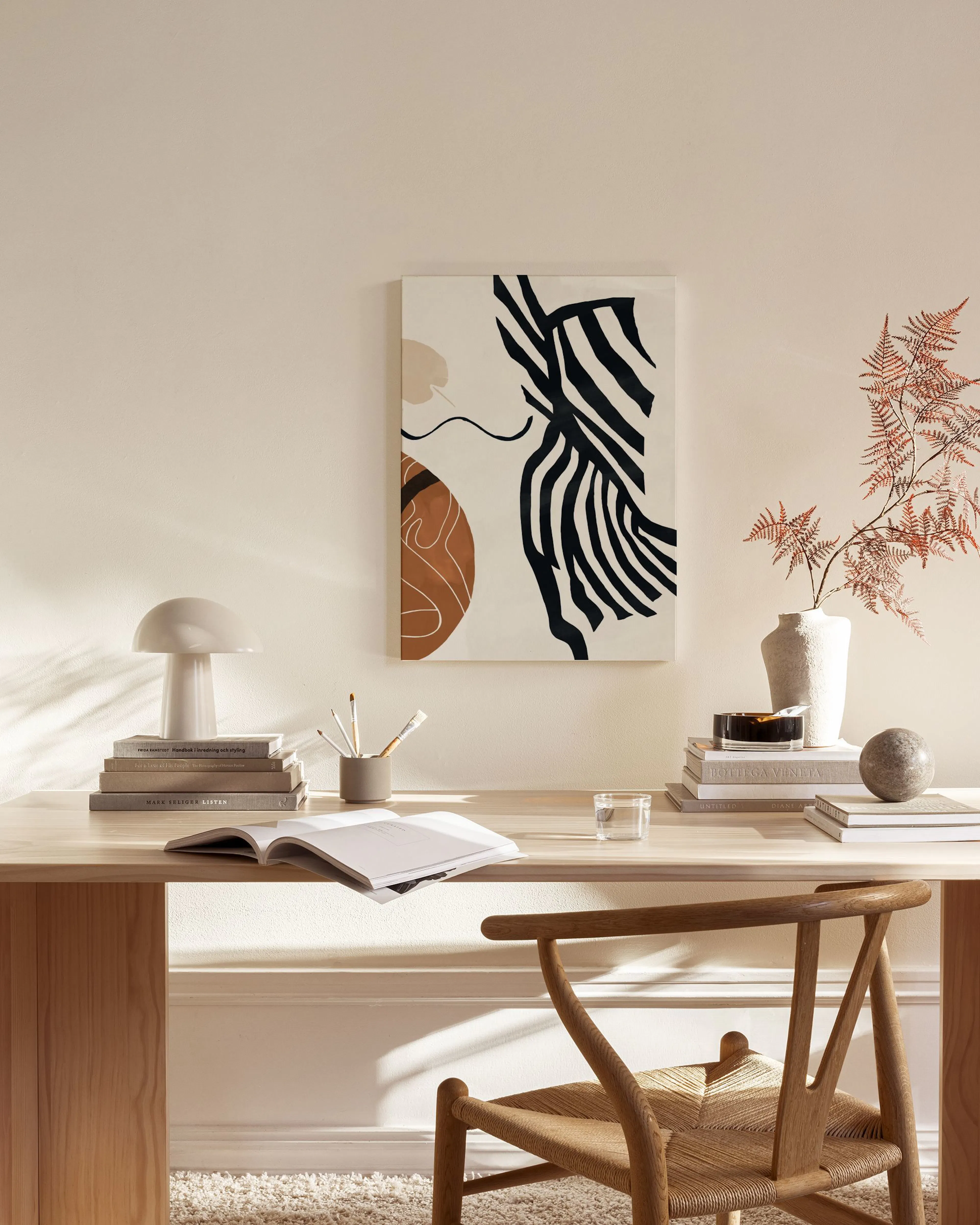 Canvas met zwarte strepen, bruine organische vormen en beige accenten, hangend in een neutrale woonkamer.