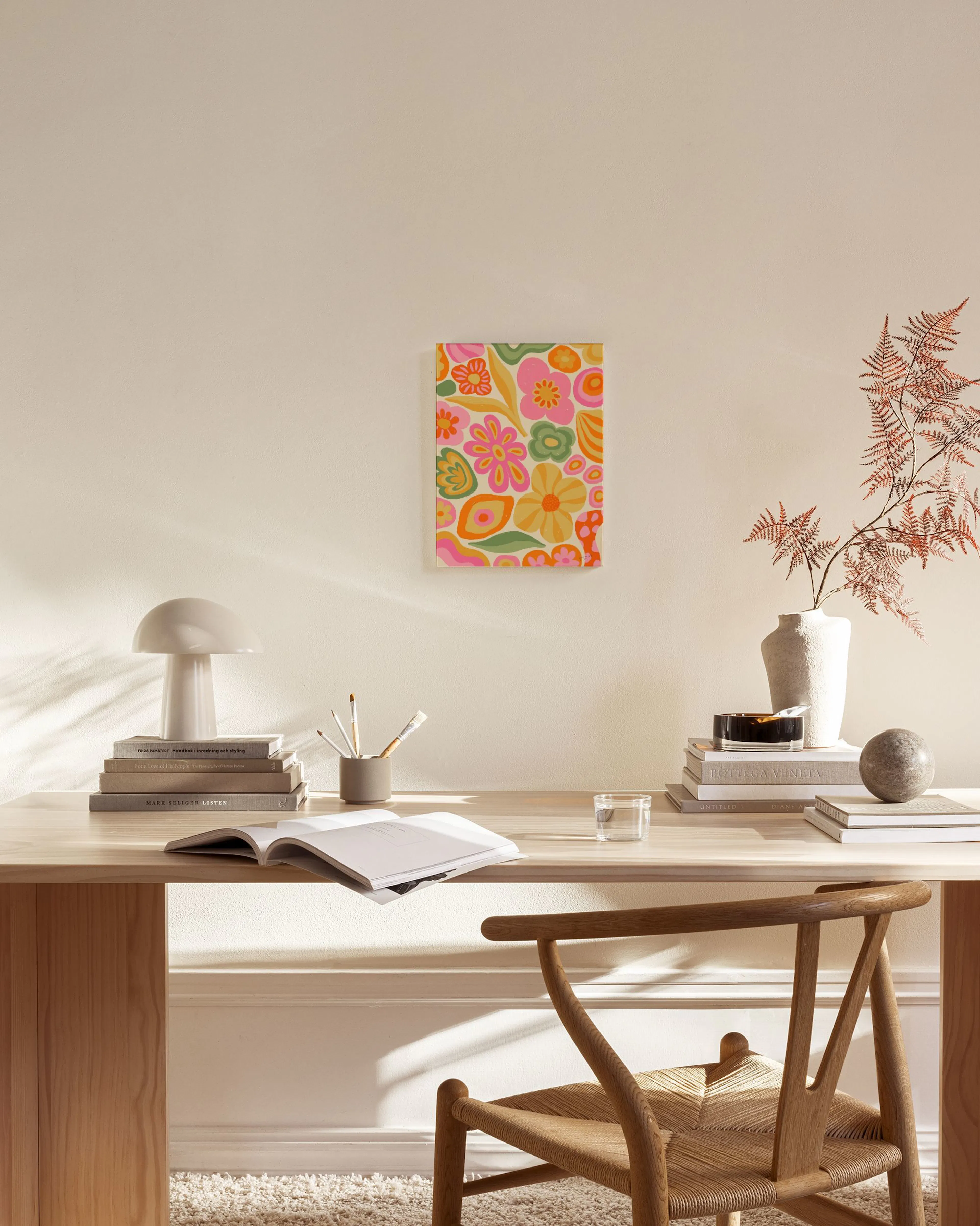 Retro canvastavla med färgglada blommor i rosa, gult och grönt, hänger ovanför en träbänk i ett modernt vardagsrum.