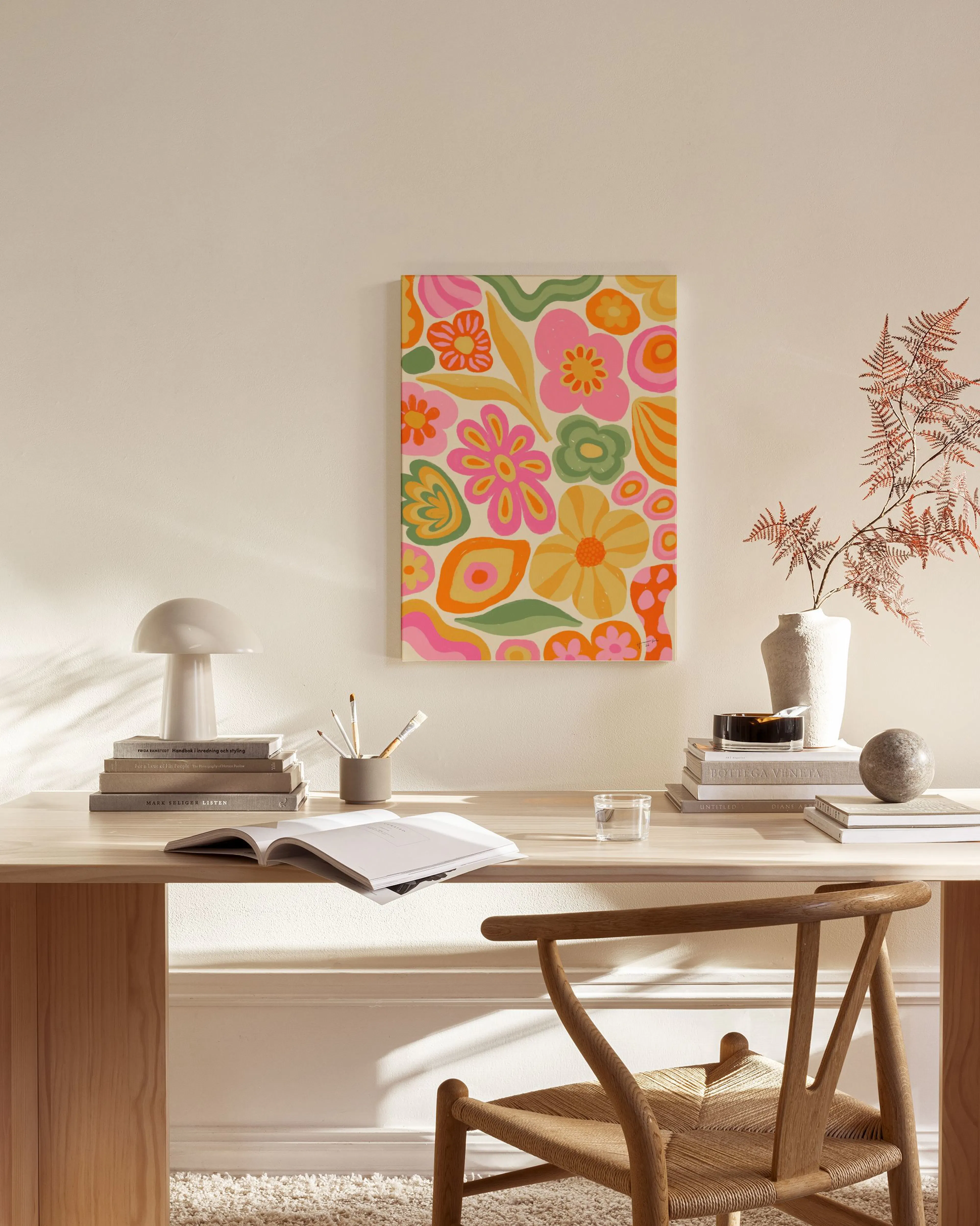 Canvas met kleurrijke abstracte bloemen en organische vormen, hangend boven een houten dressoir in een lichte woonkamer.