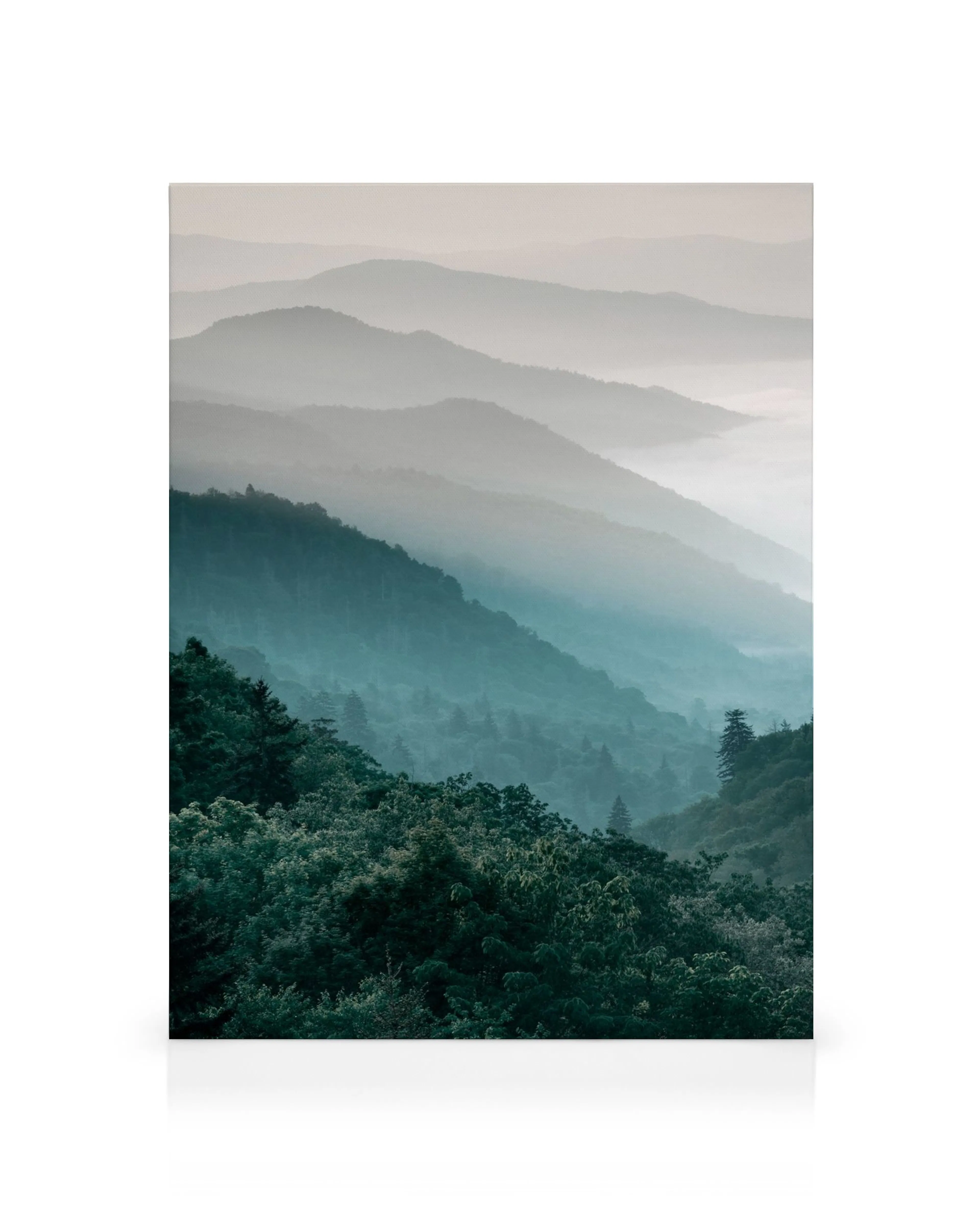 Misty forest mountain landscape canvas print with lush green trees and blue-grey mountain peaks fading into the distance.