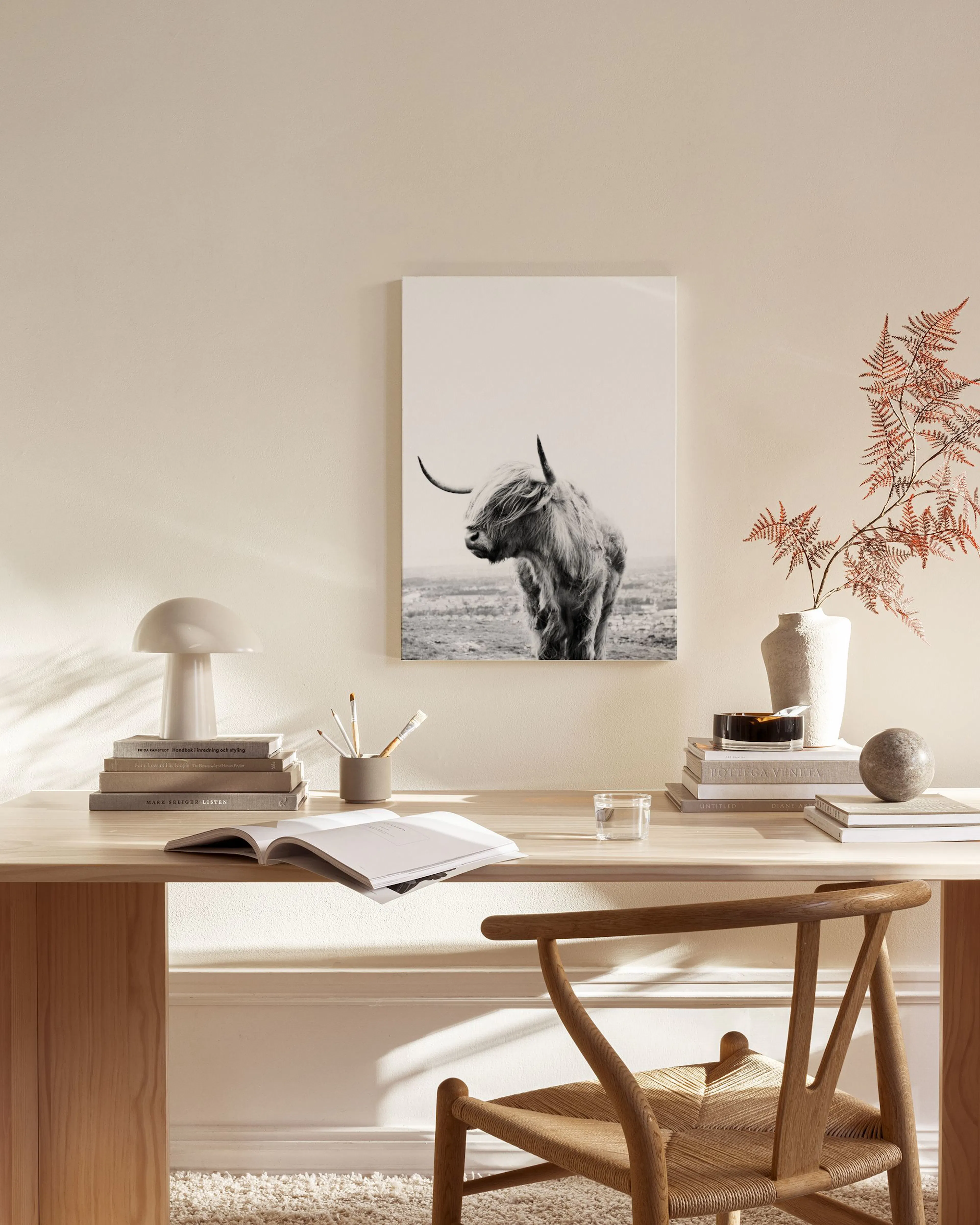 Zwart-witte canvas van een Schotse hooglander, hangend in een neutrale woonkamer boven een dressoir.