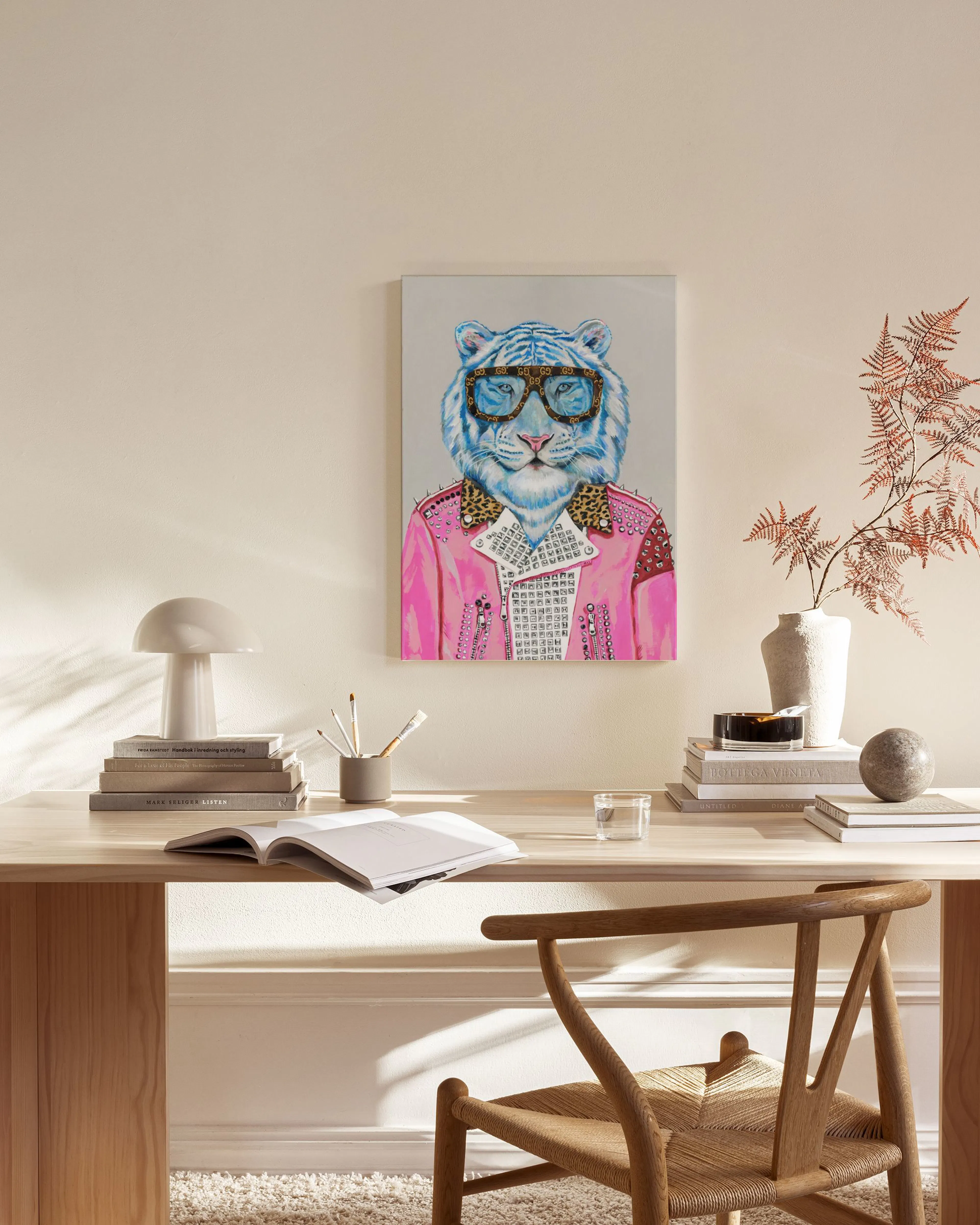 A blue tiger wearing sunglasses and a pink jacket, on a canvas print hanging in a modern living room.