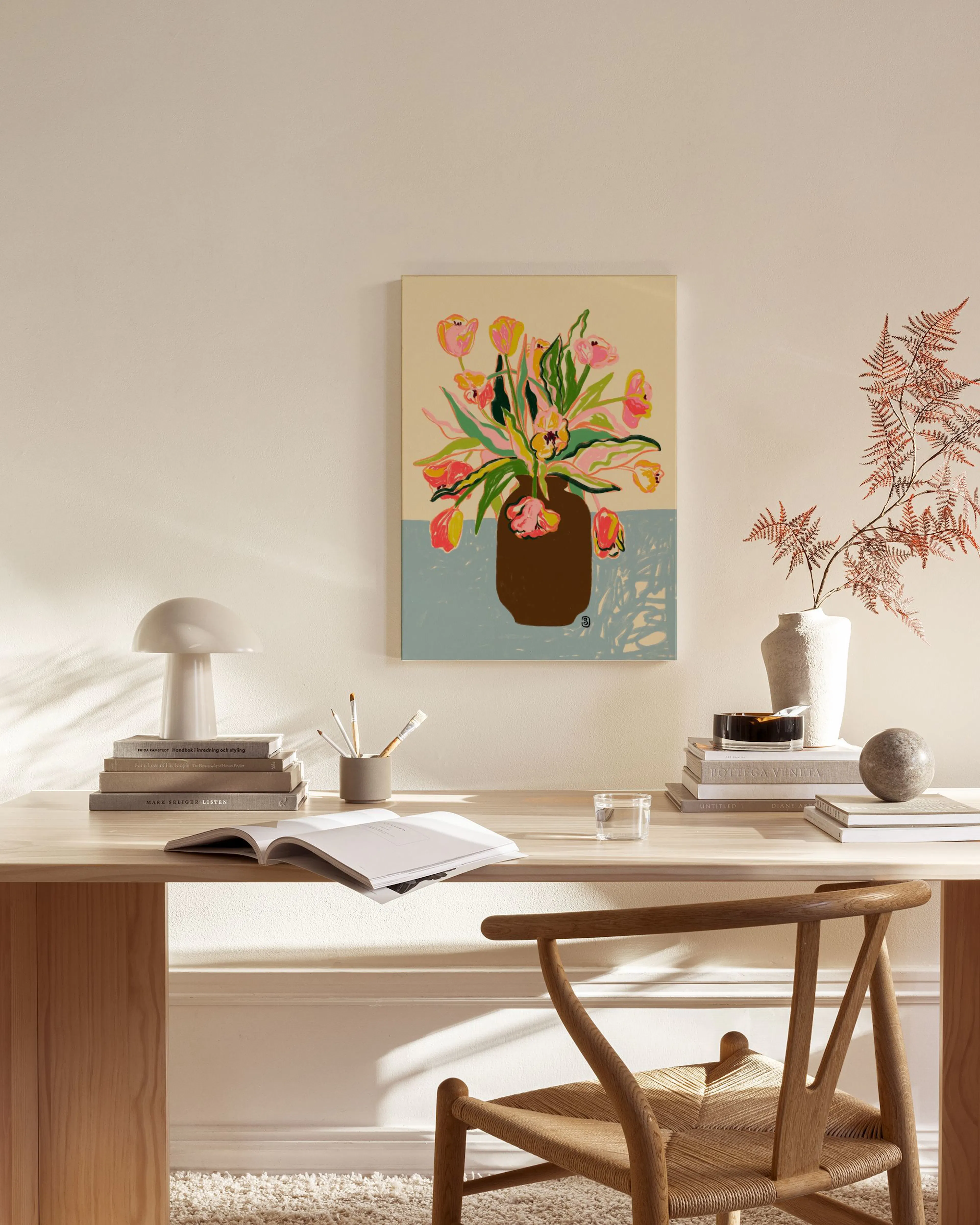 Stampa su tela con vaso marrone e tulipani rosa e gialli, appesa in un soggiorno moderno sopra una panca in legno.