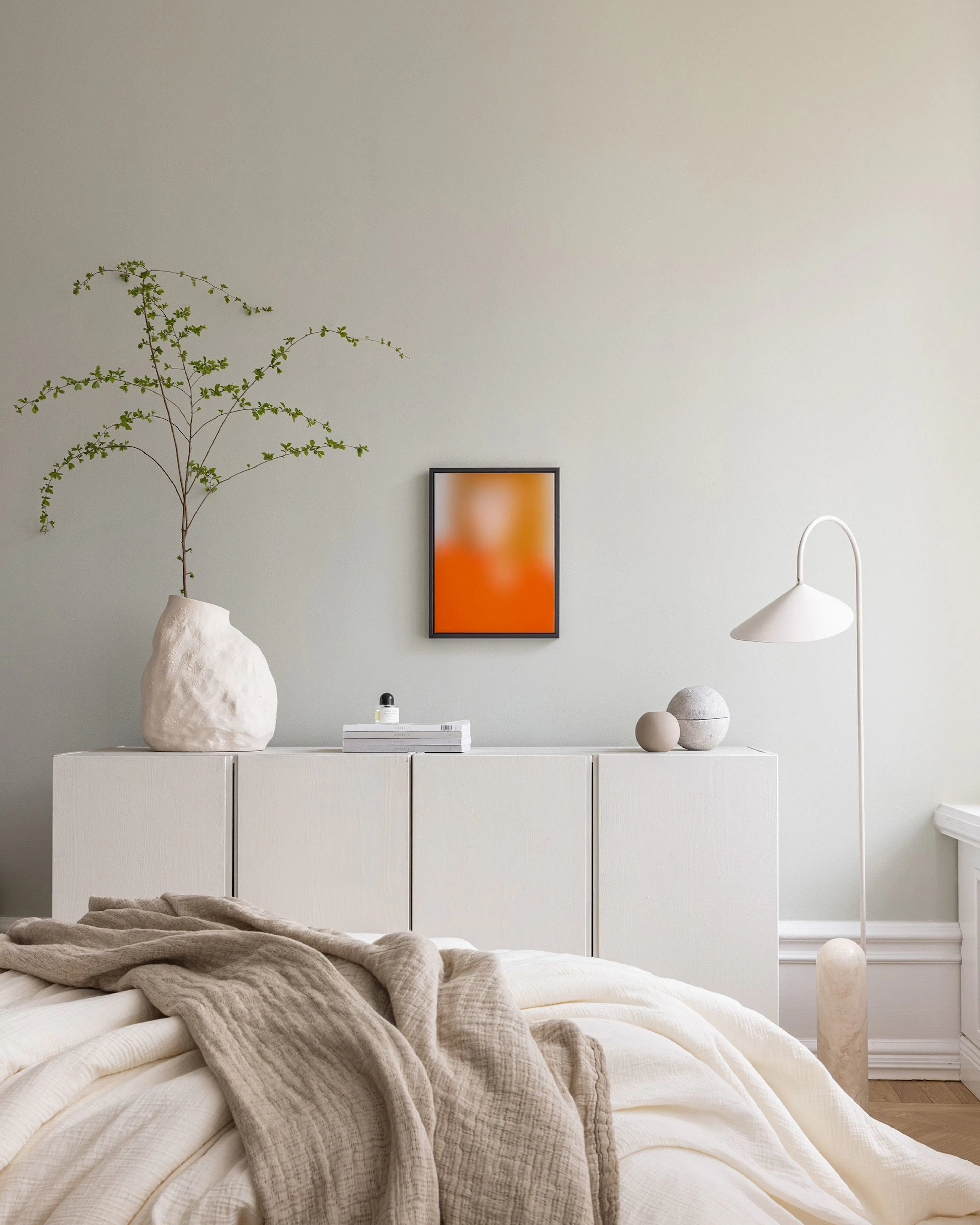 Orange and yellow blurred canvas print hanging above a wooden console table in a neutral living room.