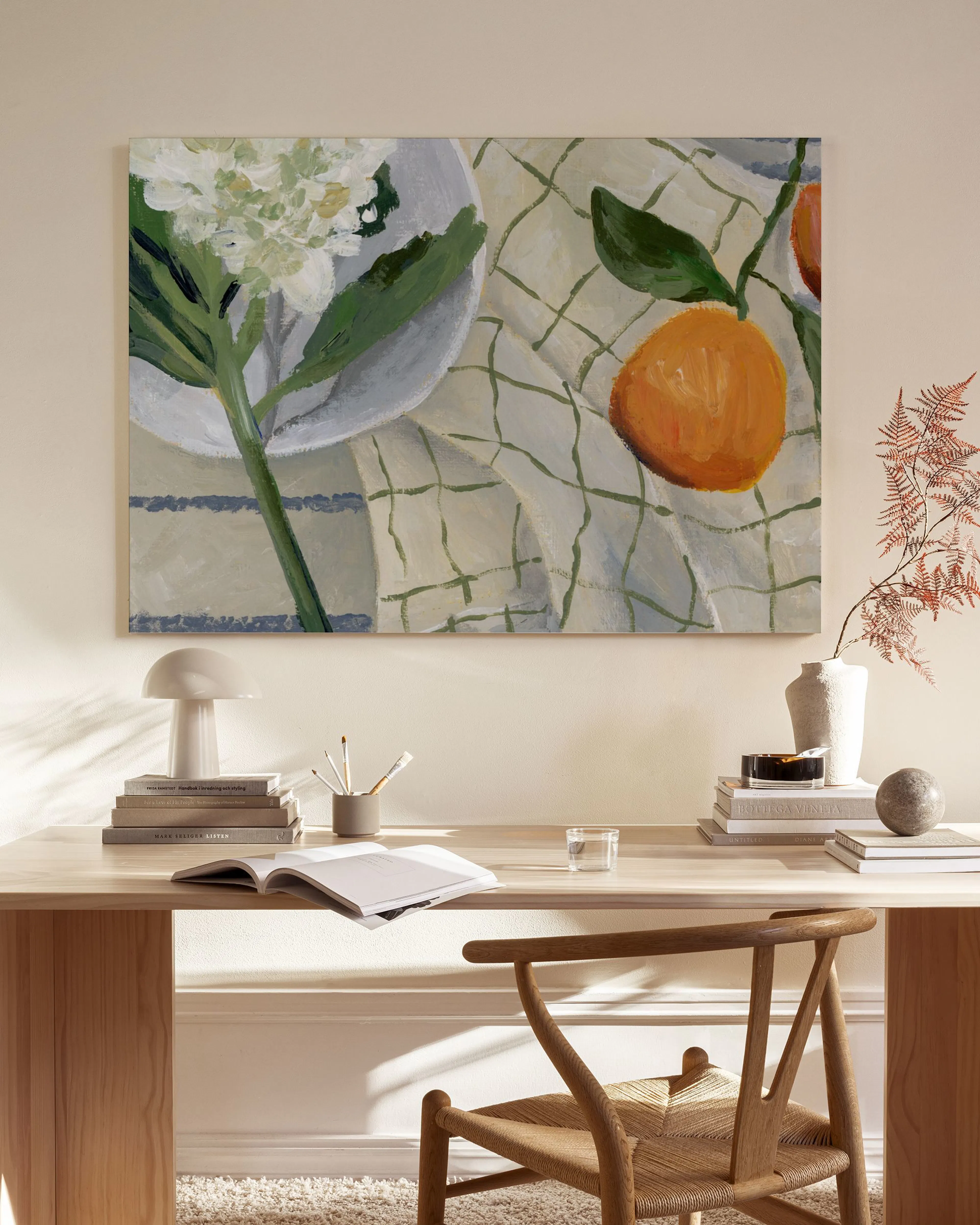 Still life canvas print with a white flower and an orange on a checkered tablecloth, displayed above a wooden console.