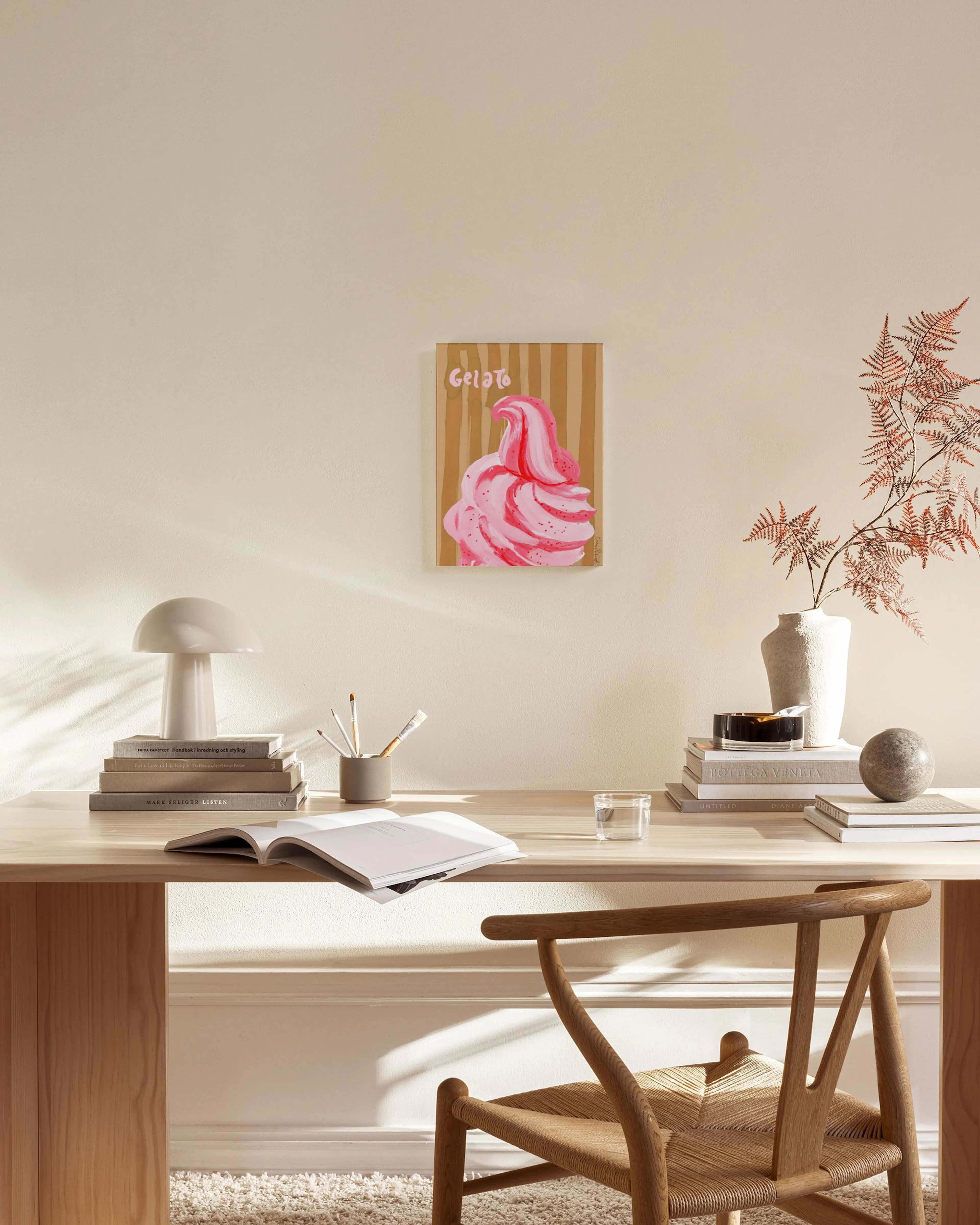 A colorful gelato illustration with pink swirls and red speckles on a striped background, hanging in a minimalist living room.
