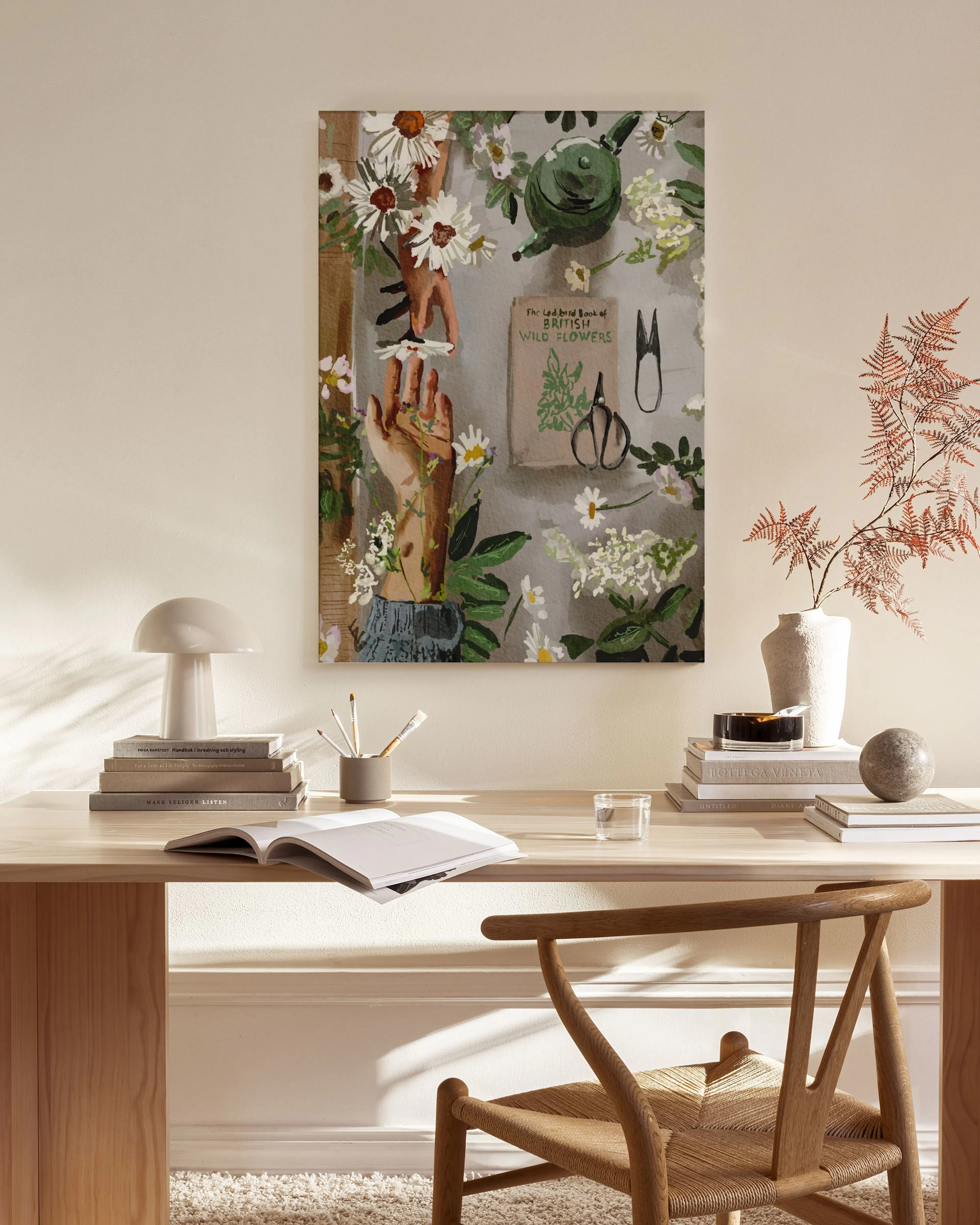 A canvas print of hands tending to white wildflowers and herbs, with gardening tools, hanging in a minimalist living room.