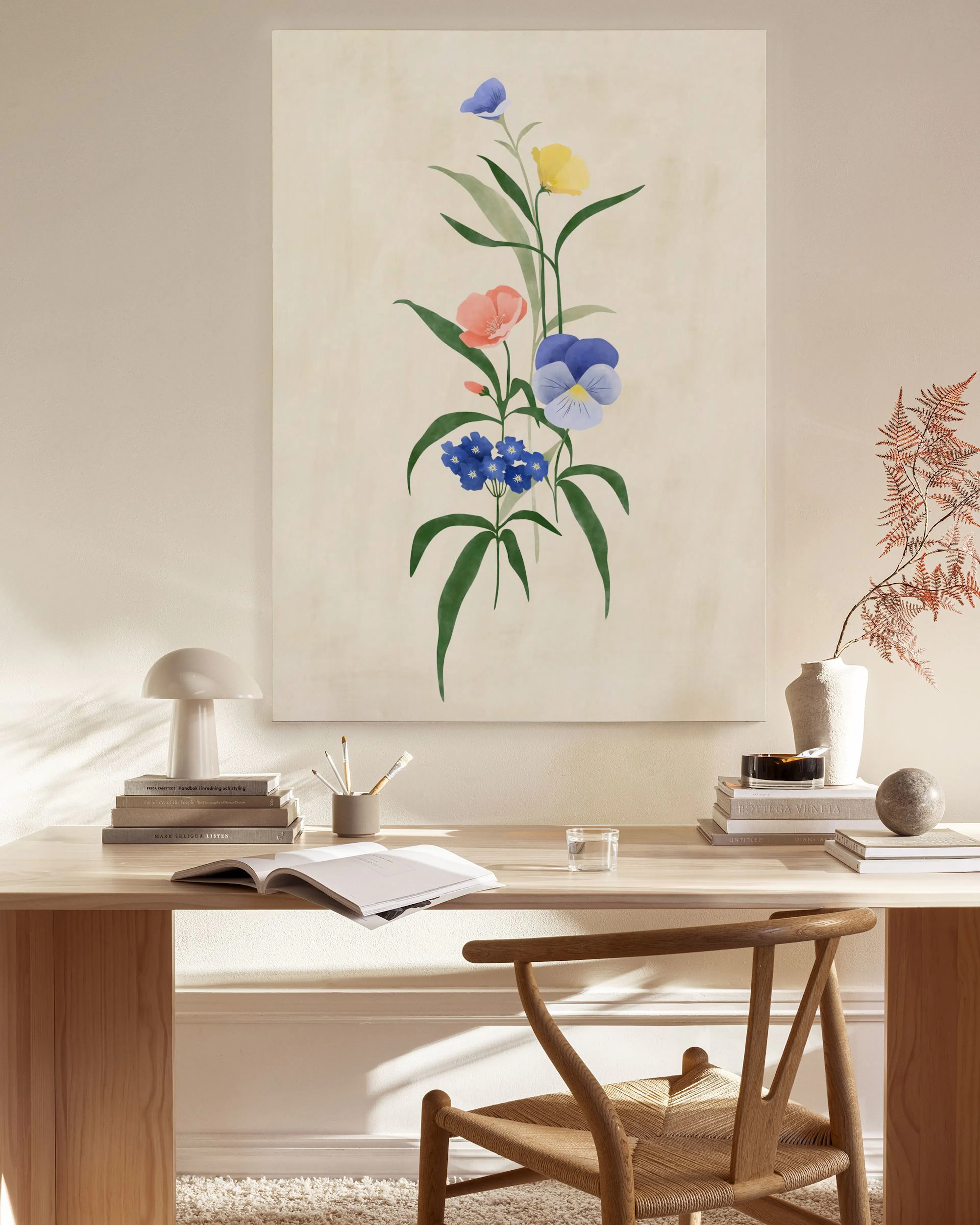 A canvas print of a vibrant floral bouquet with blue, yellow, and red flowers, displayed above a wooden console in a bright room