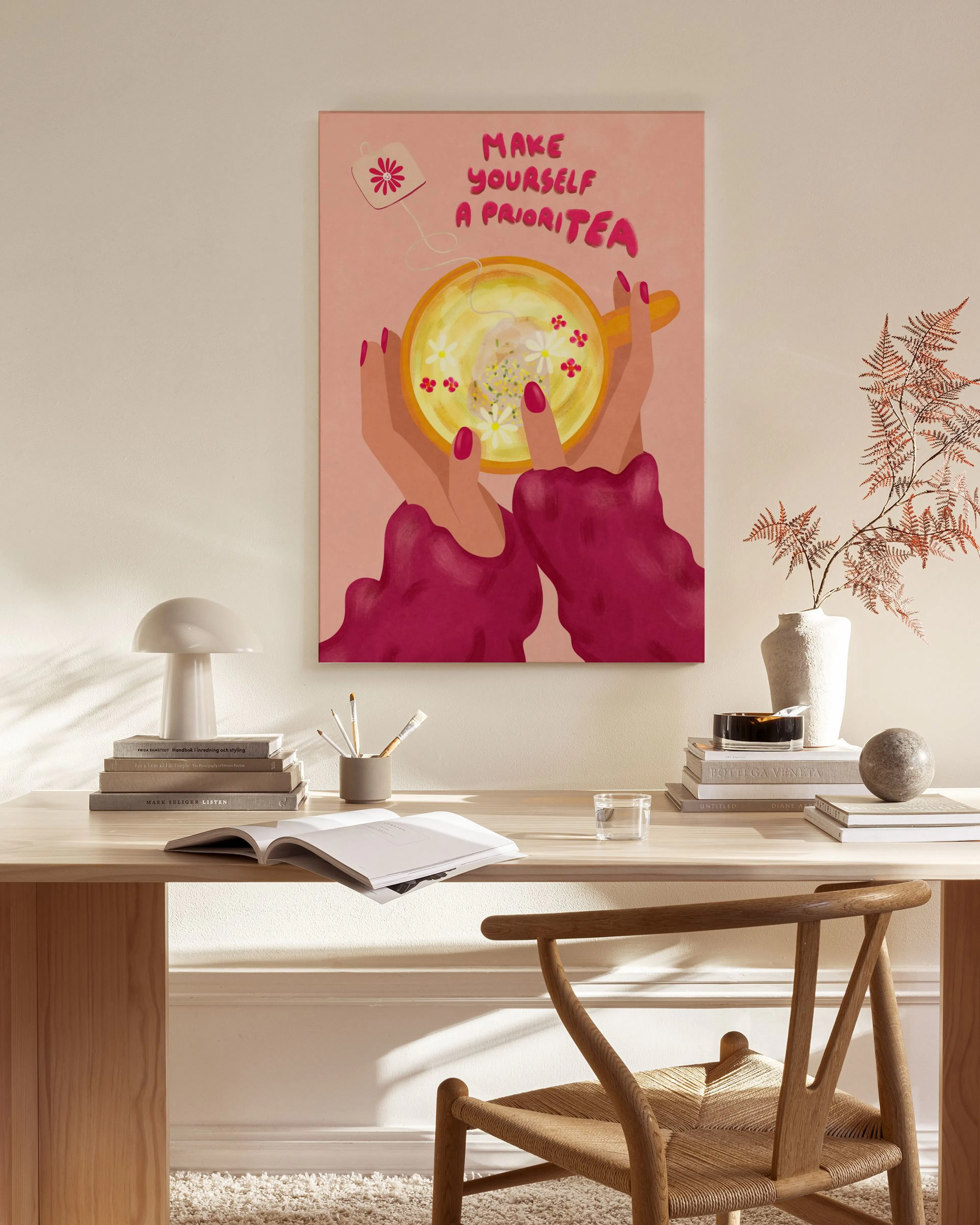 A canvas print of hands holding a tea cup with Make Yourself a PrioriTEA text, displayed in a modern living room.