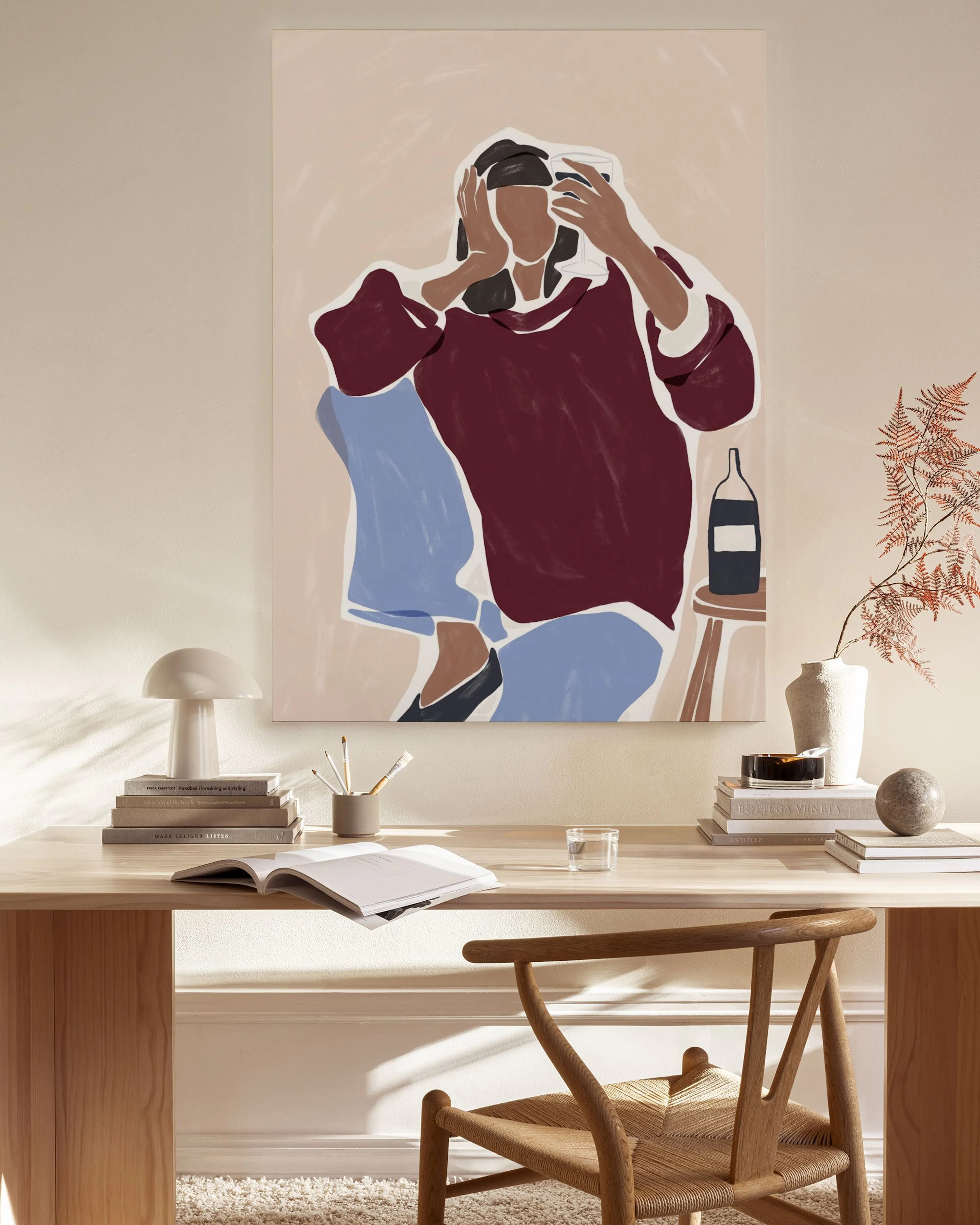Abstract canvas print of a person in a maroon top and blue pants on a light background, hanging in a modern living room.