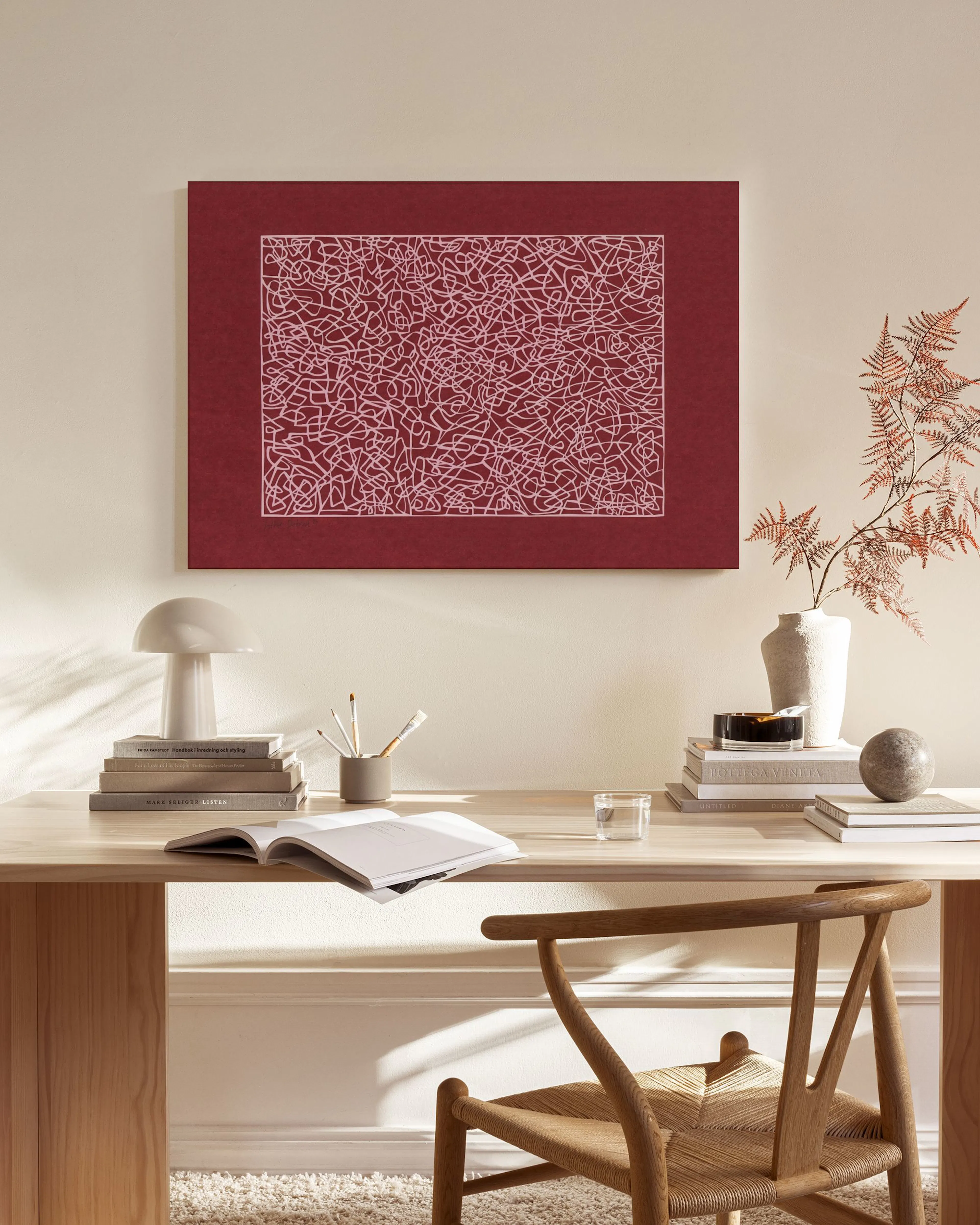 A crimson canvas print with white freehand abstract lines, hanging above a wooden console table in a minimalist living room.