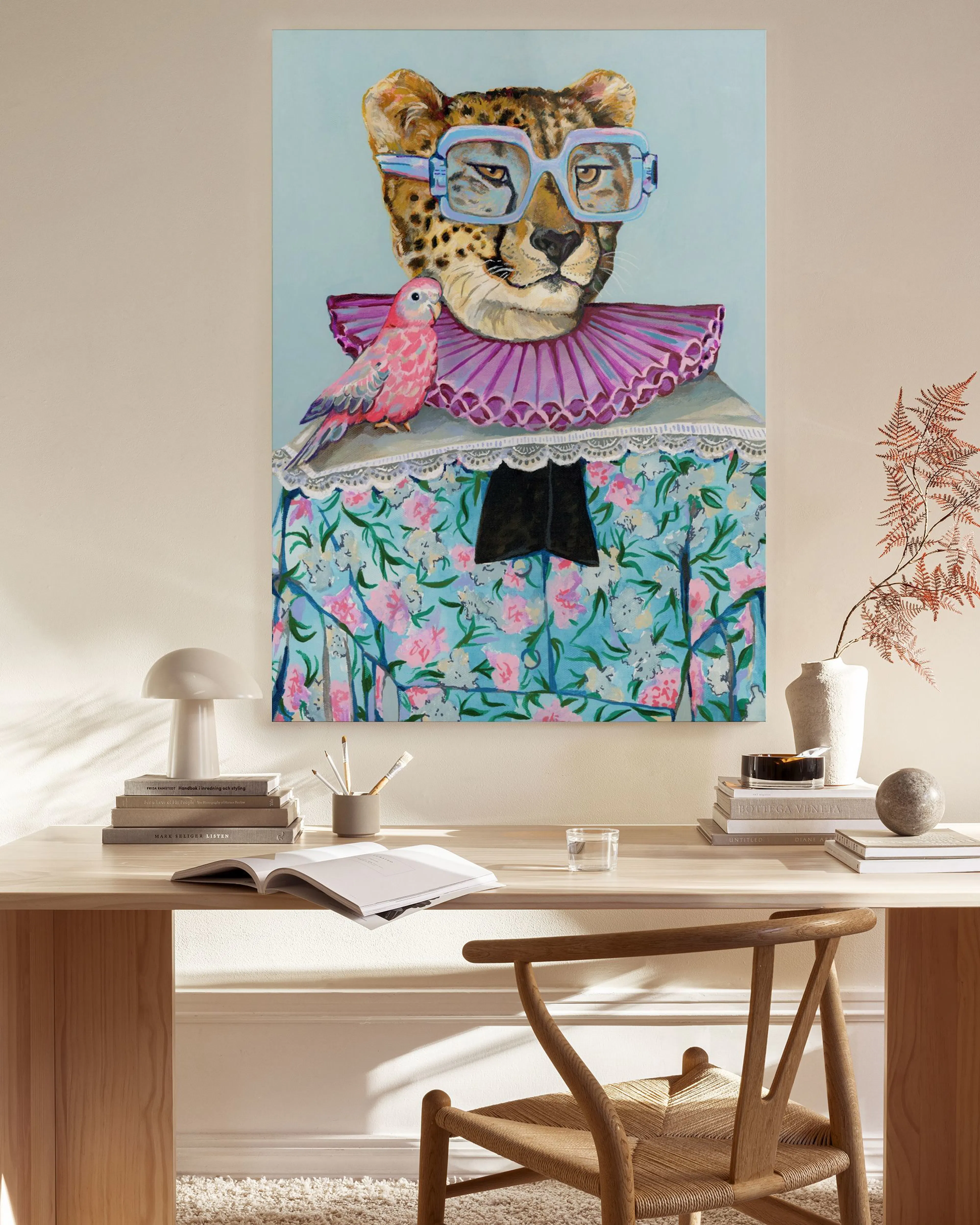Lienzo de un guepardo con gafas y gorguera rosa, con un perico, colgado en una sala de estar moderna.
