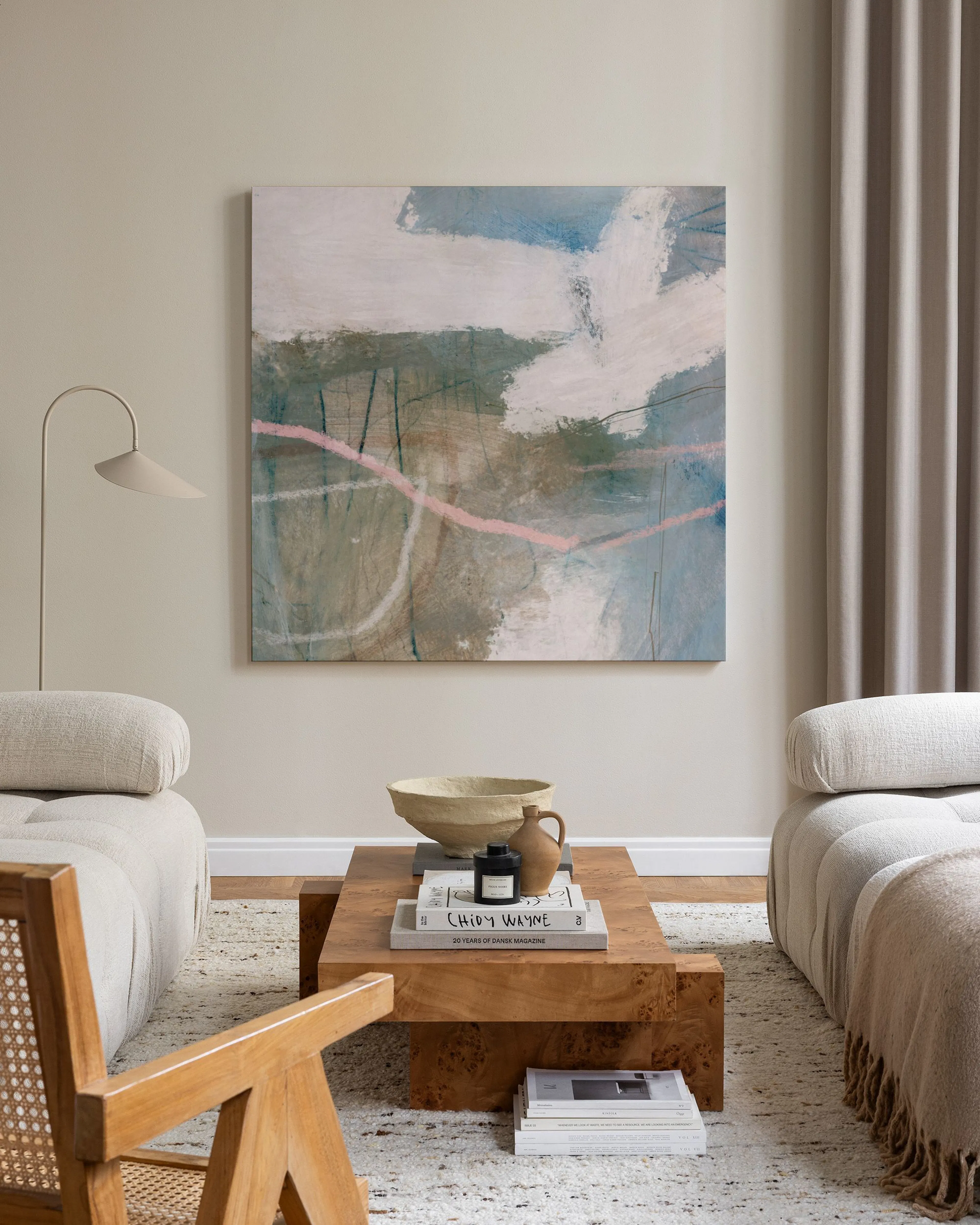 Tela decorativa abstrata com pinceladas em tons de azul, verde, bege e rosa, pendurada numa sala de estar minimalista.