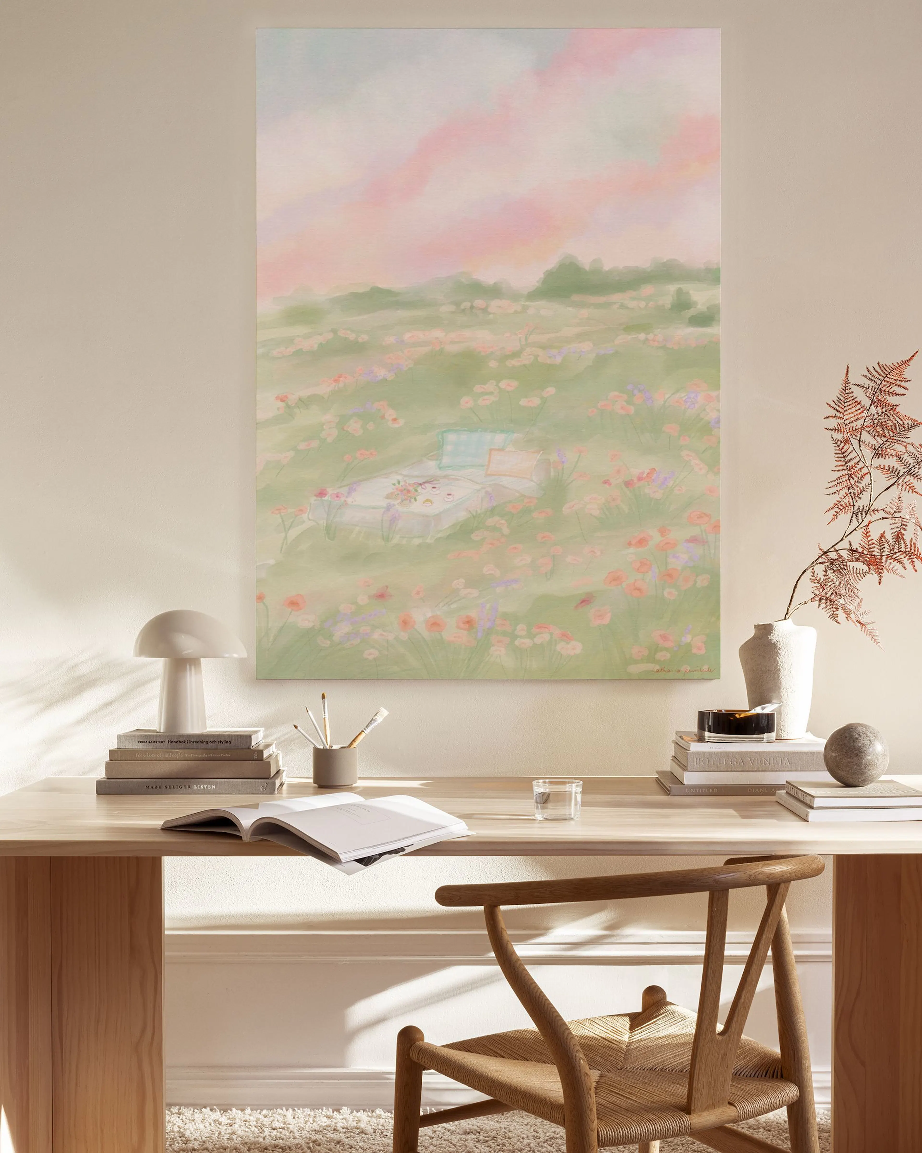 Canvas met roze heuvels en een groen bloemenveld, hangend in een lichte woonkamer boven een houten meubel.
