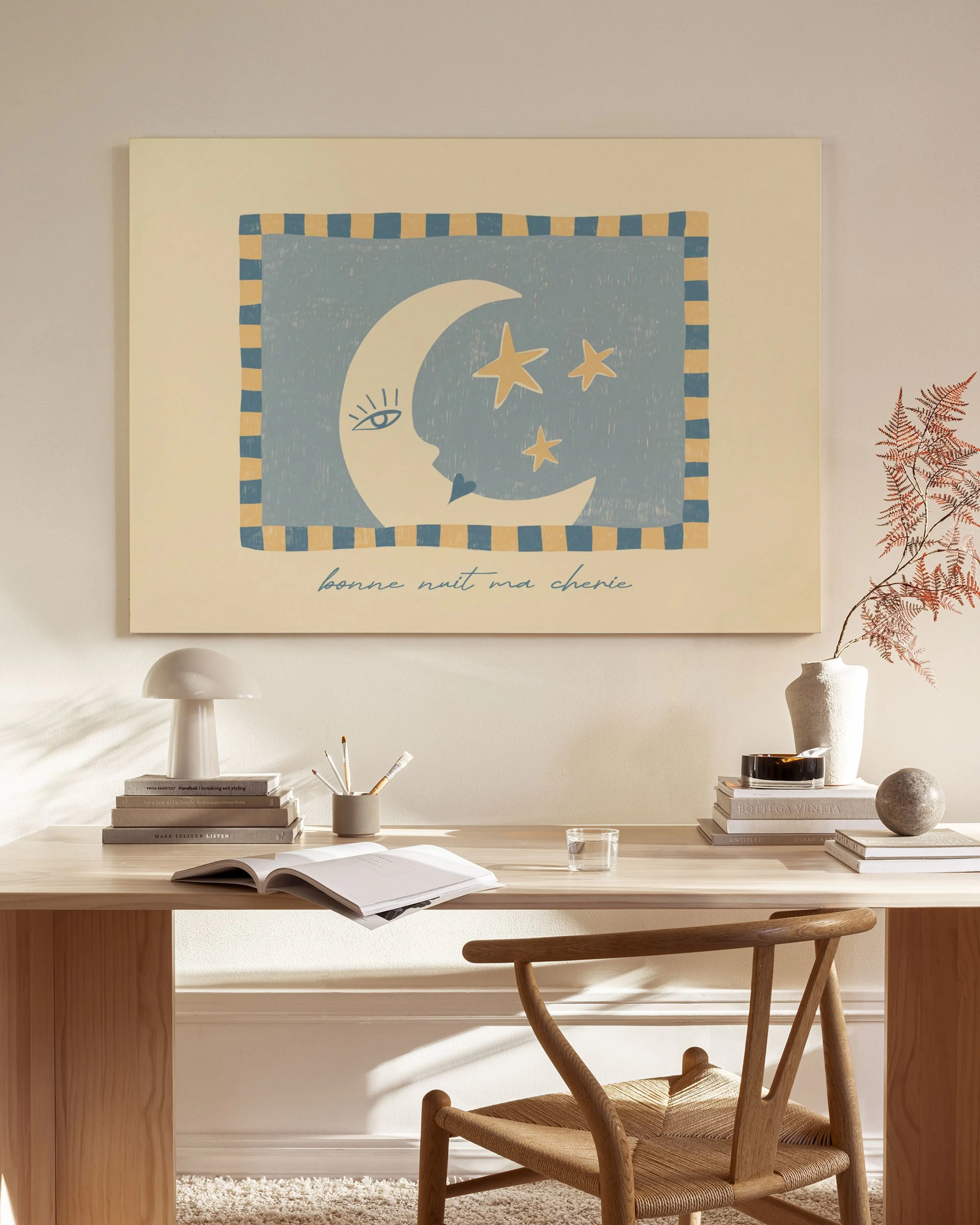 Canvas met blauw en beige illustratie van een halve maan en sterren, hangend boven een houten dressoir in een woonkamer.