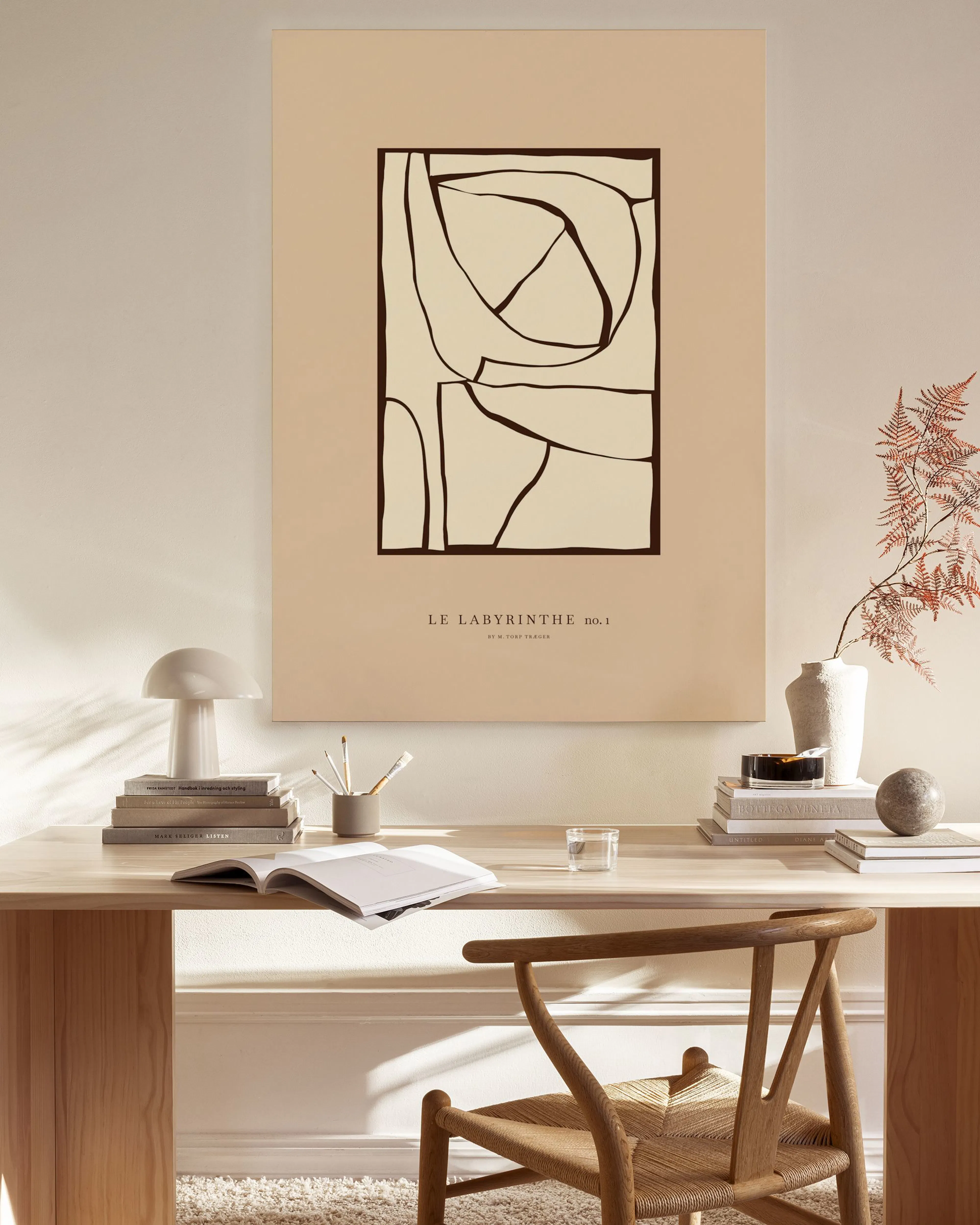 Lienzo abstracto con formas orgánicas negras sobre fondo beige, colgado en una sala de estar moderna sobre un mueble bajo de mad