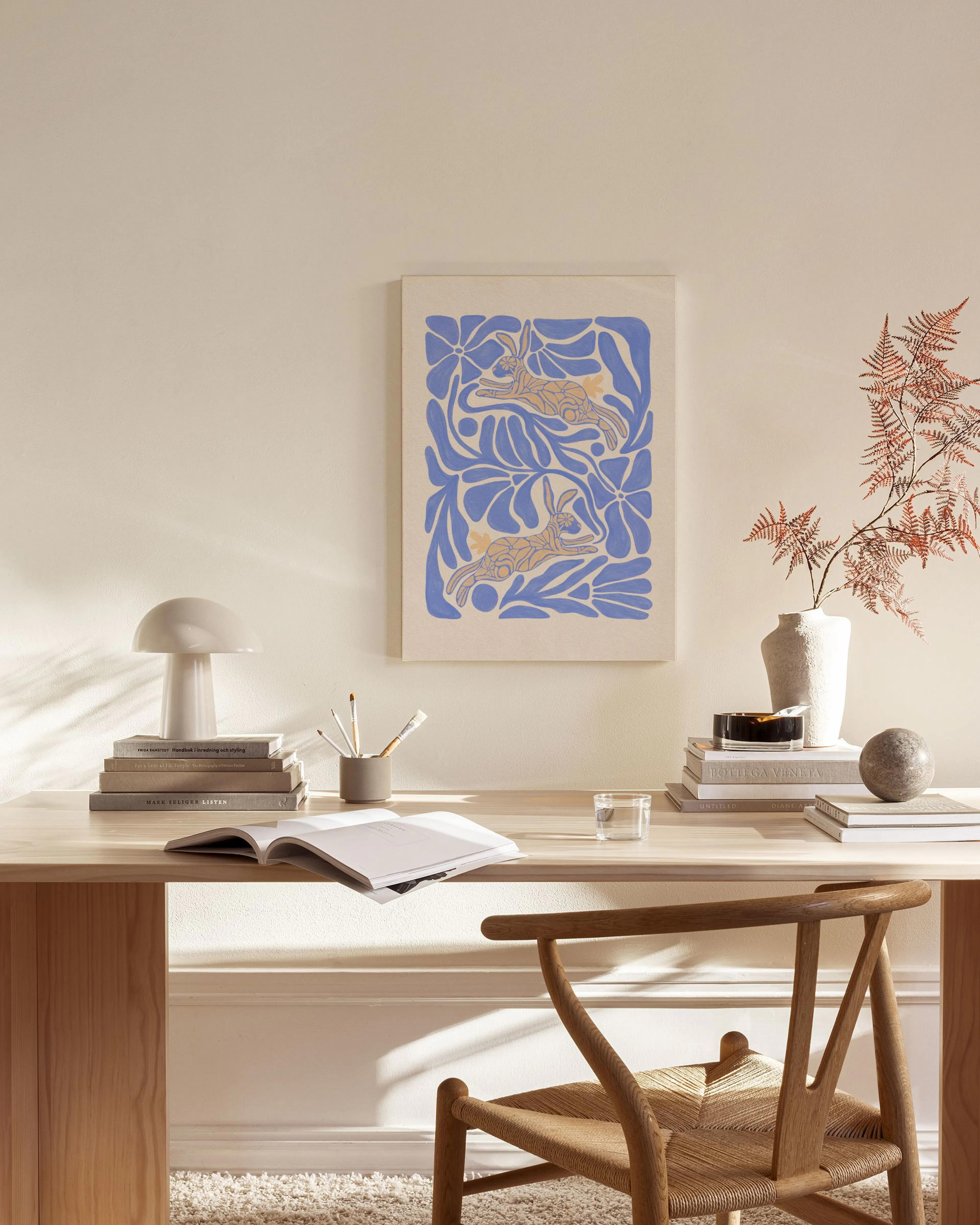 Canvas met blauwe bladeren en twee oranje konijnen, hangend in een neutrale woonkamer boven een salontafel.