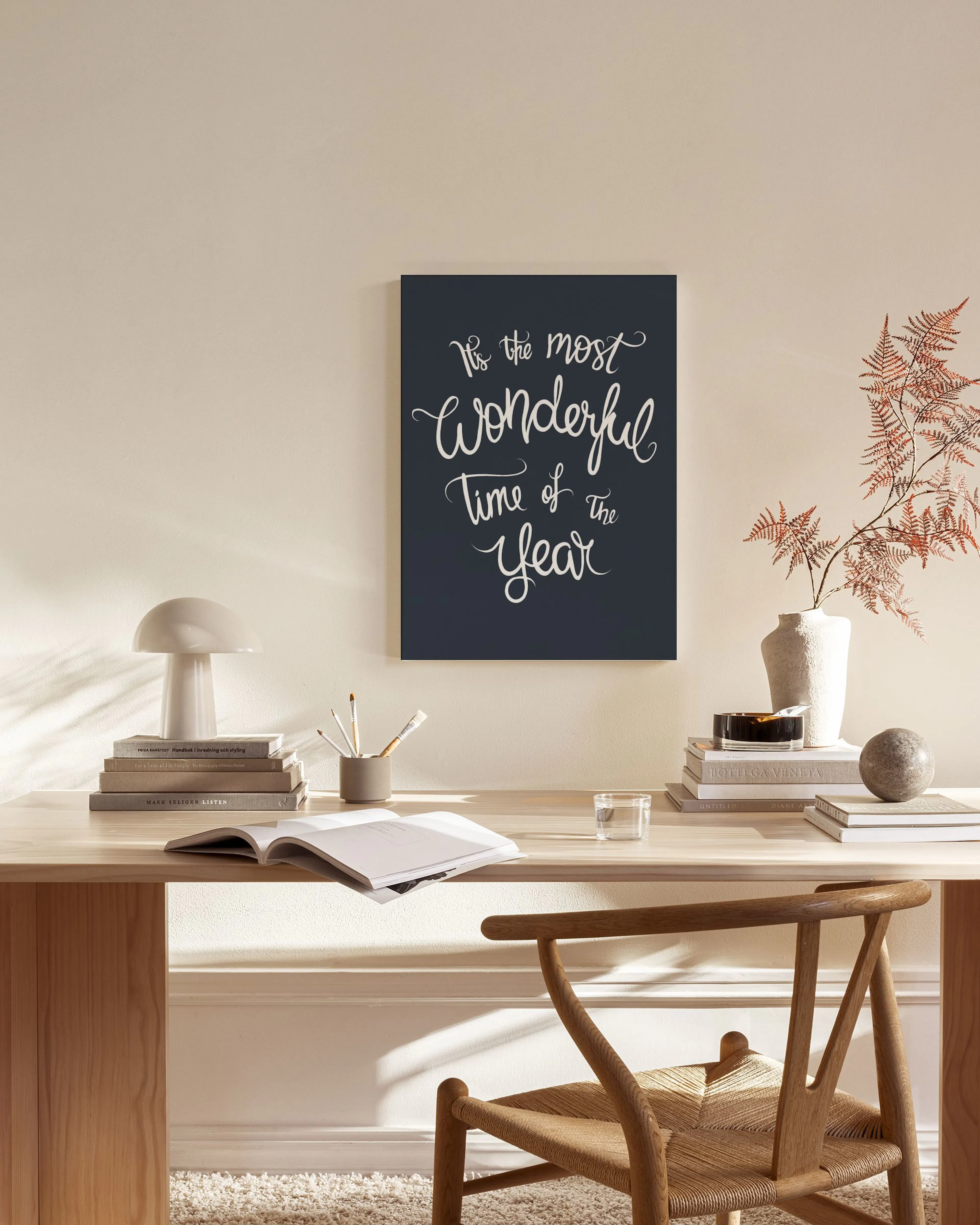 Lienzo con la frase Its the most wonderful time of the year en blanco sobre fondo azul oscuro, colgado en una sala de estar.