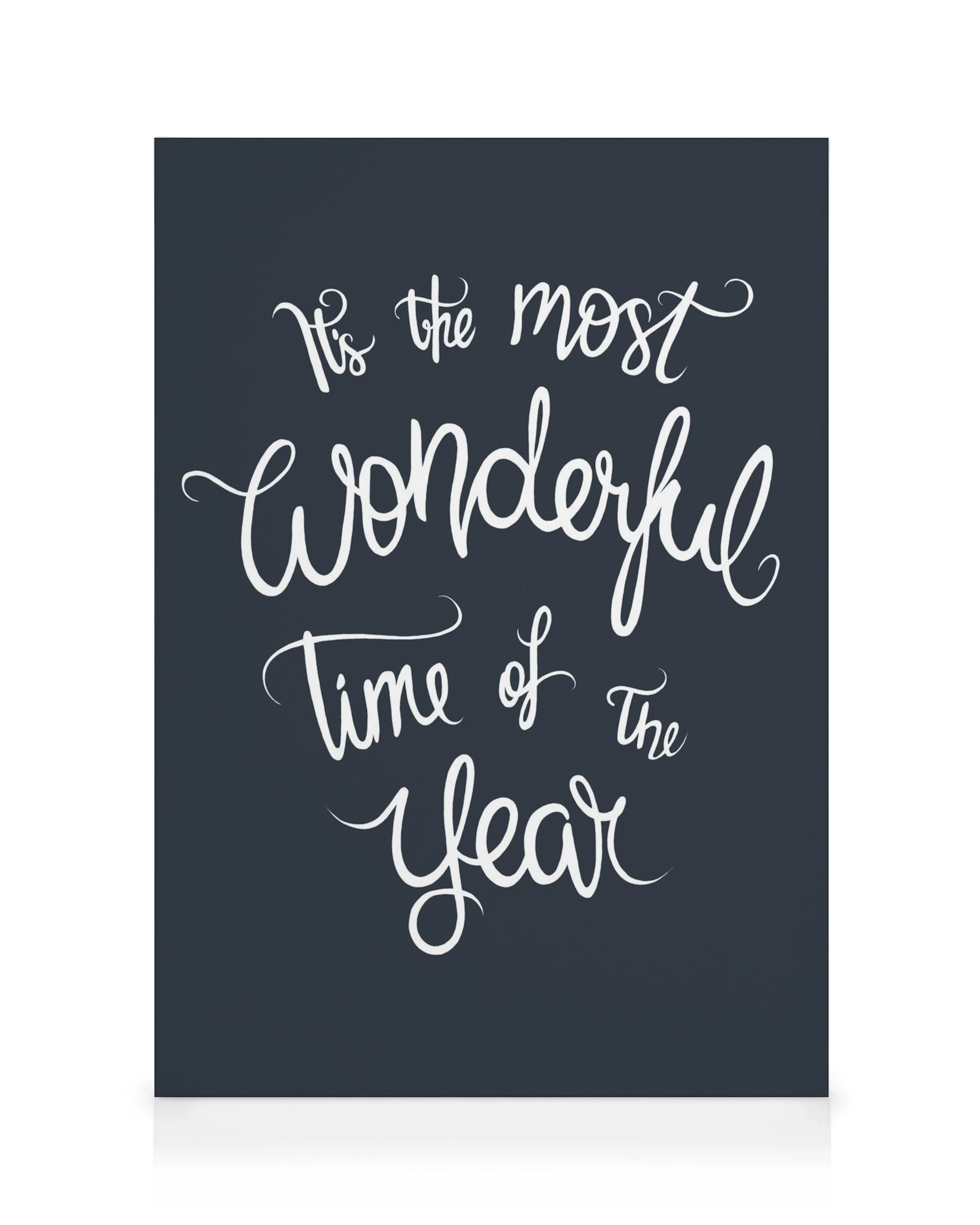 Lienzo The Most Wonderful Time Of The Year con texto blanco cursivo sobre fondo azul oscuro. Arte de pared festivo.