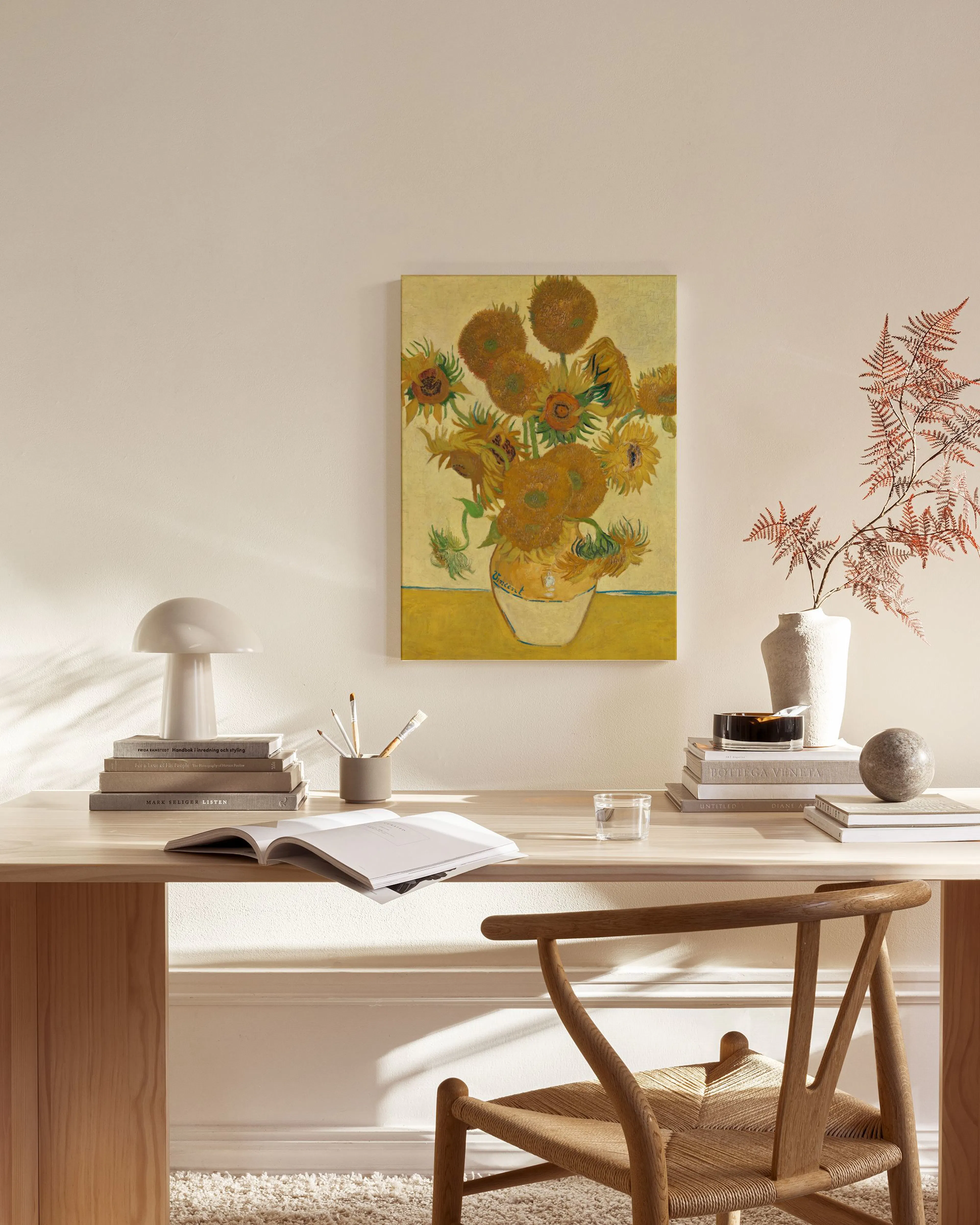 Lærred med Van Goghs Solsikker i en vase, ophængt i en minimalistisk stue over et træmøbel.