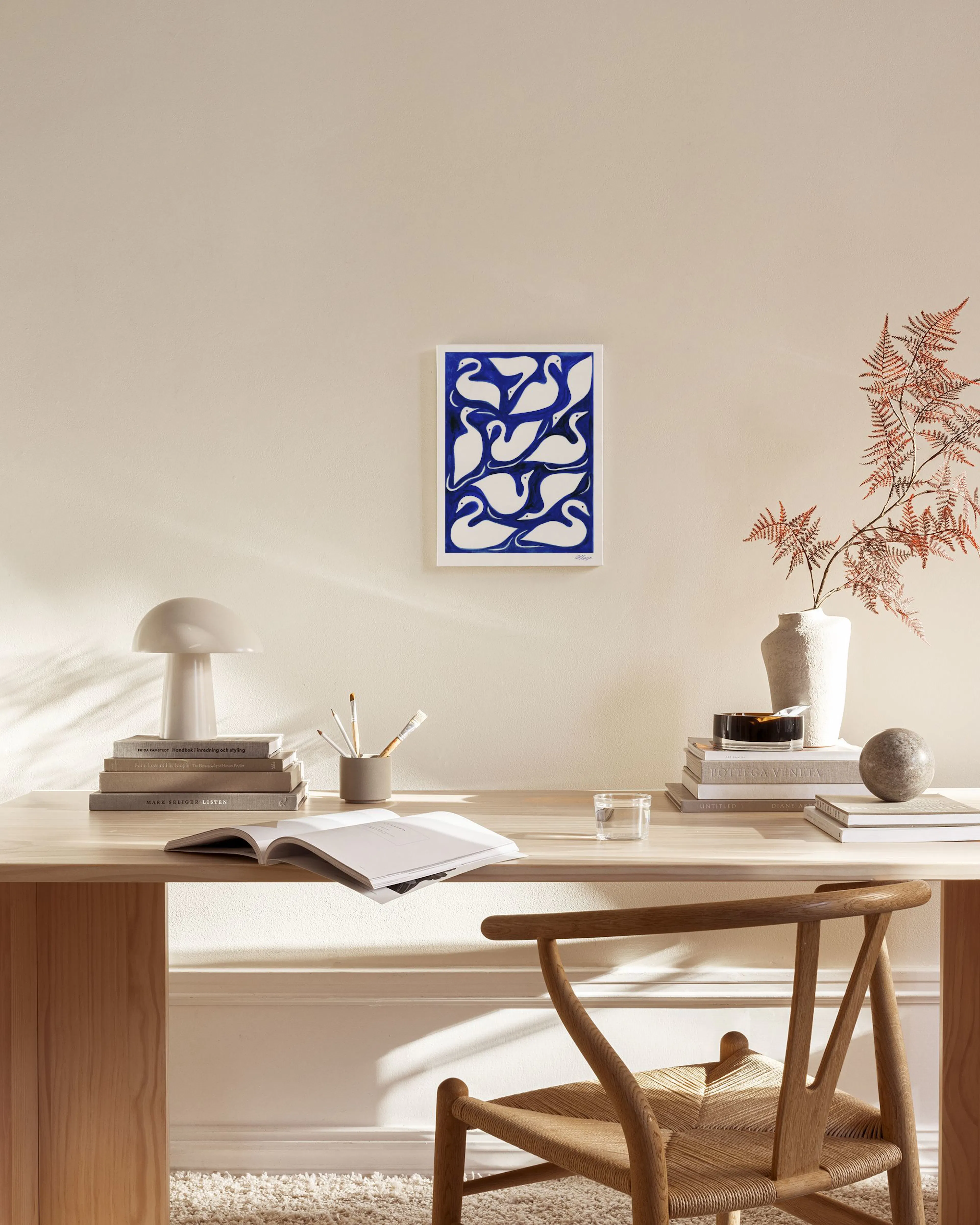 Lienzo con cisnes blancos sobre fondo azul vibrante, exhibido en una sala de estar moderna sobre un mueble de madera.