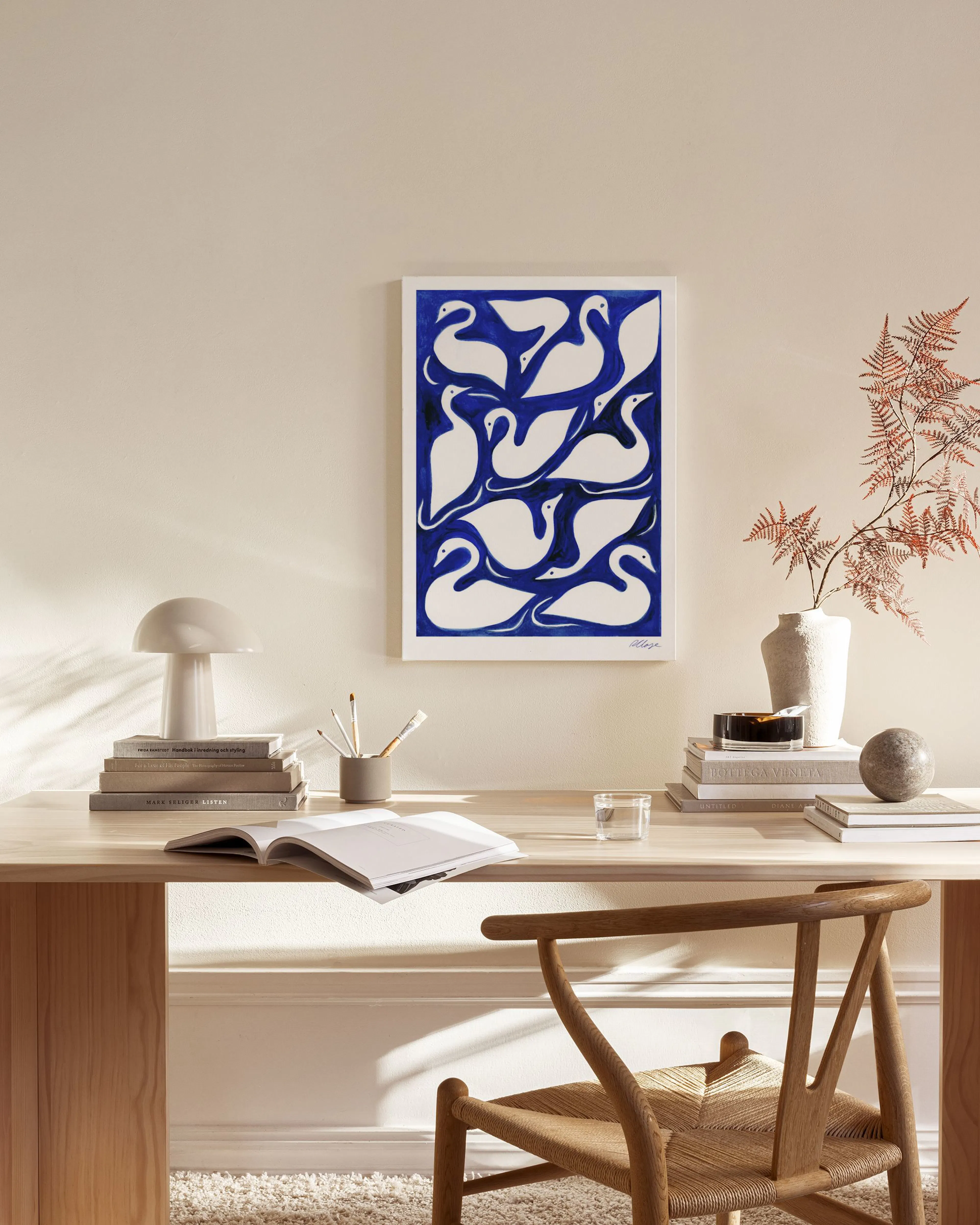Stampa su tela di cigni bianchi stilizzati su sfondo blu, appesa in un moderno soggiorno luminoso.
