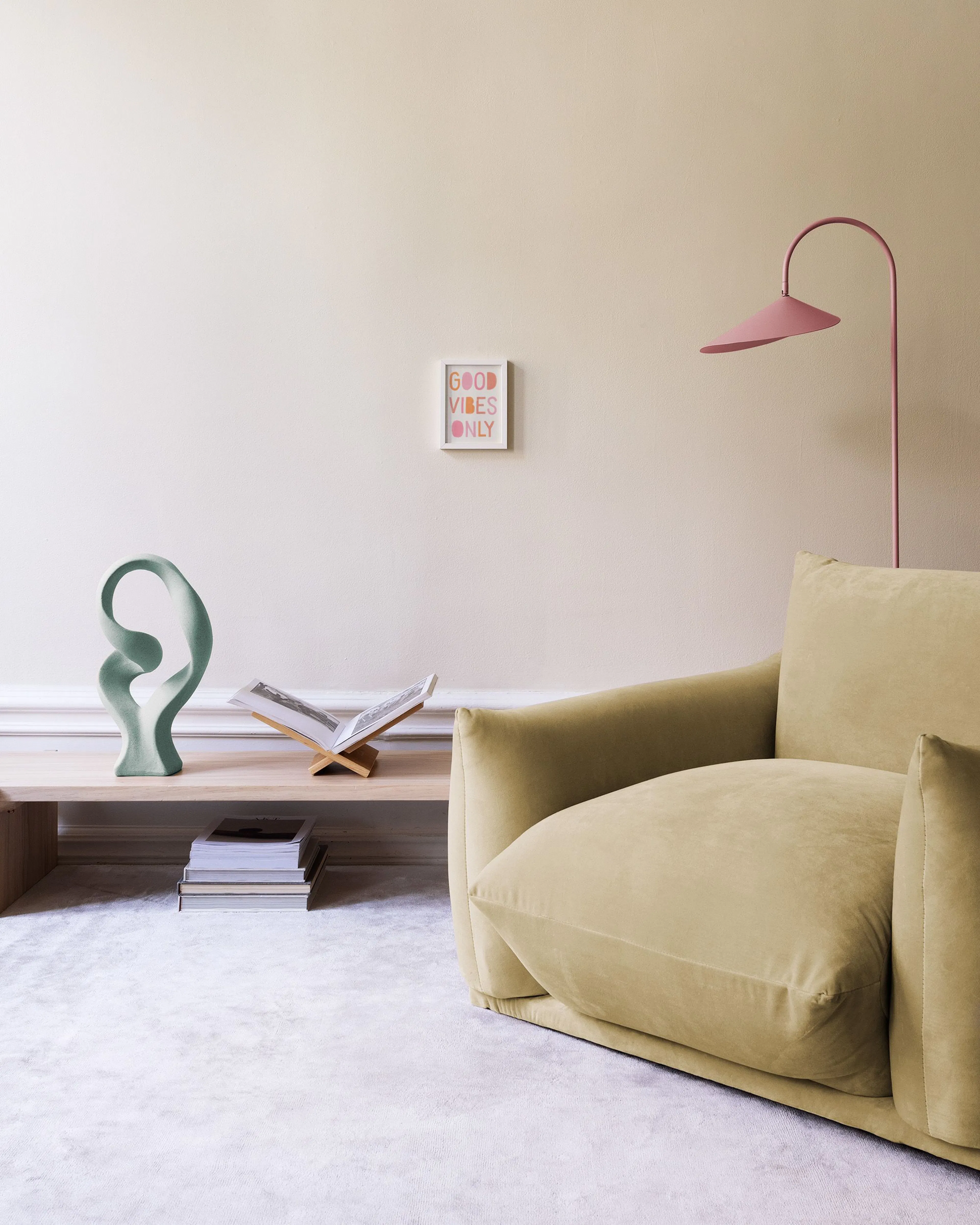 A print with GOOD VIBES ONLY in pink and orange letters, displayed on a white cabinet with a bowl and lamp.