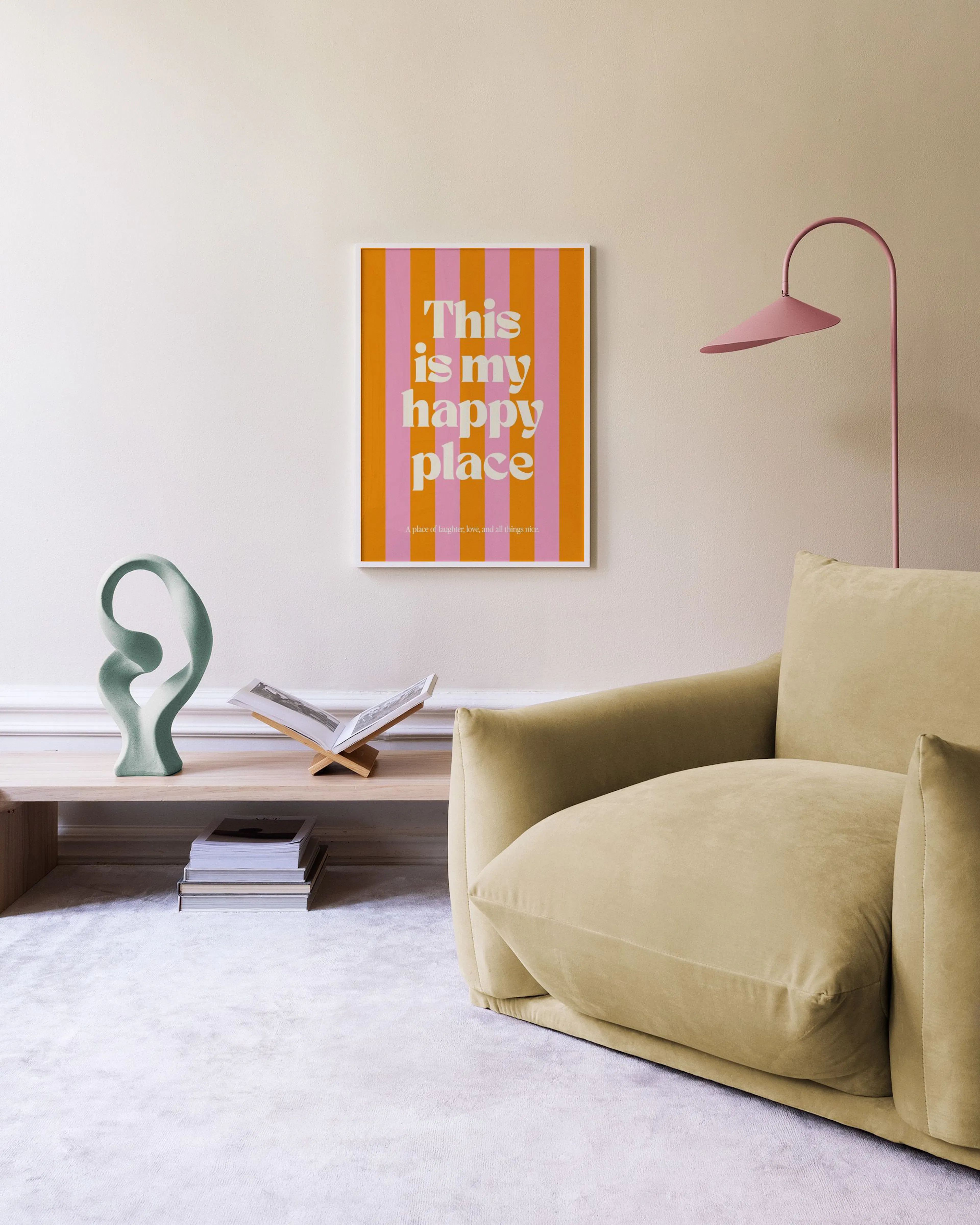 A print with orange and pink vertical stripes and the text This is my happy place in a living room with a beige sofa.
