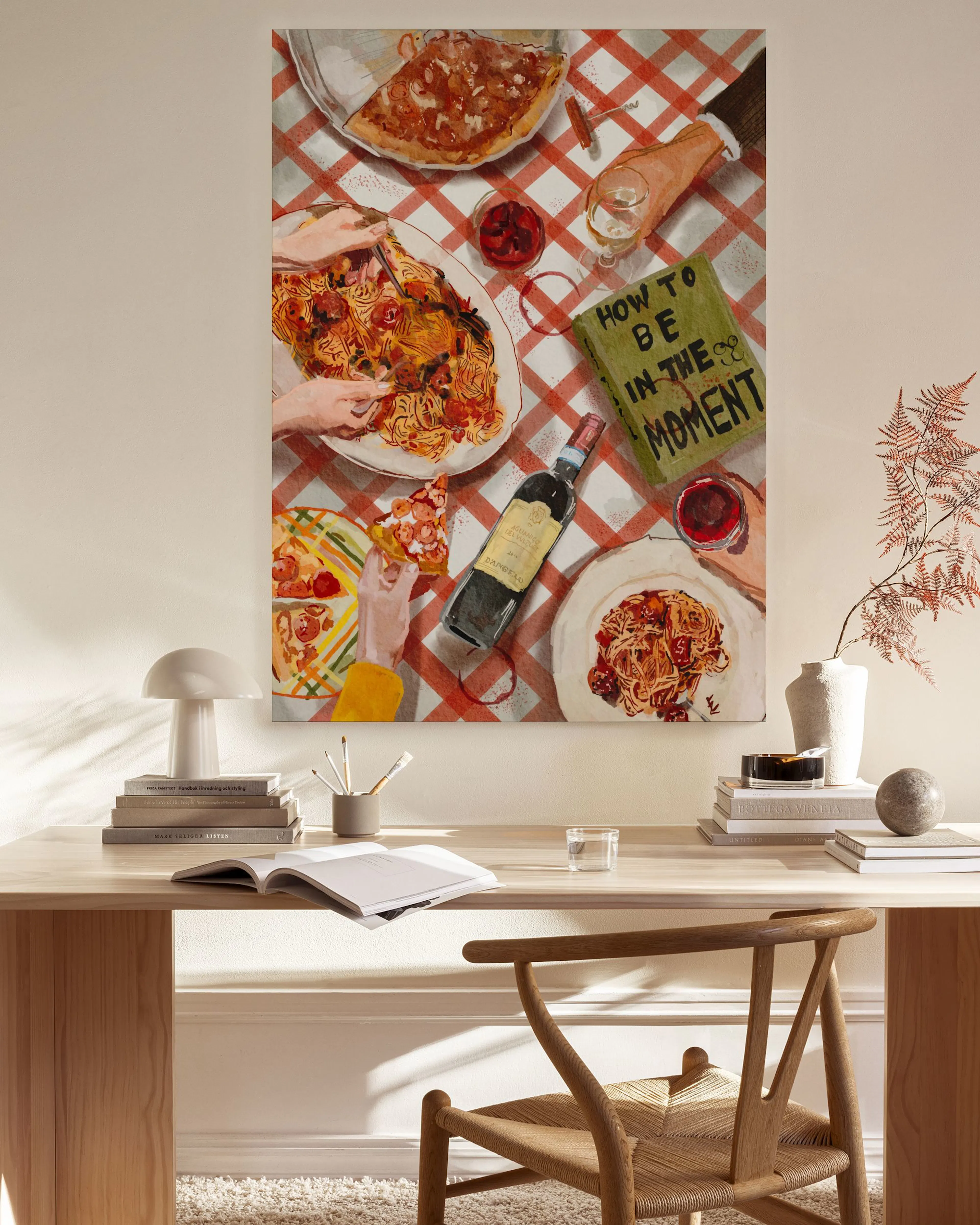 A canvas print of a dinner scene with pizza and pasta on a red and white checkered tablecloth, hanging in a modern living room.