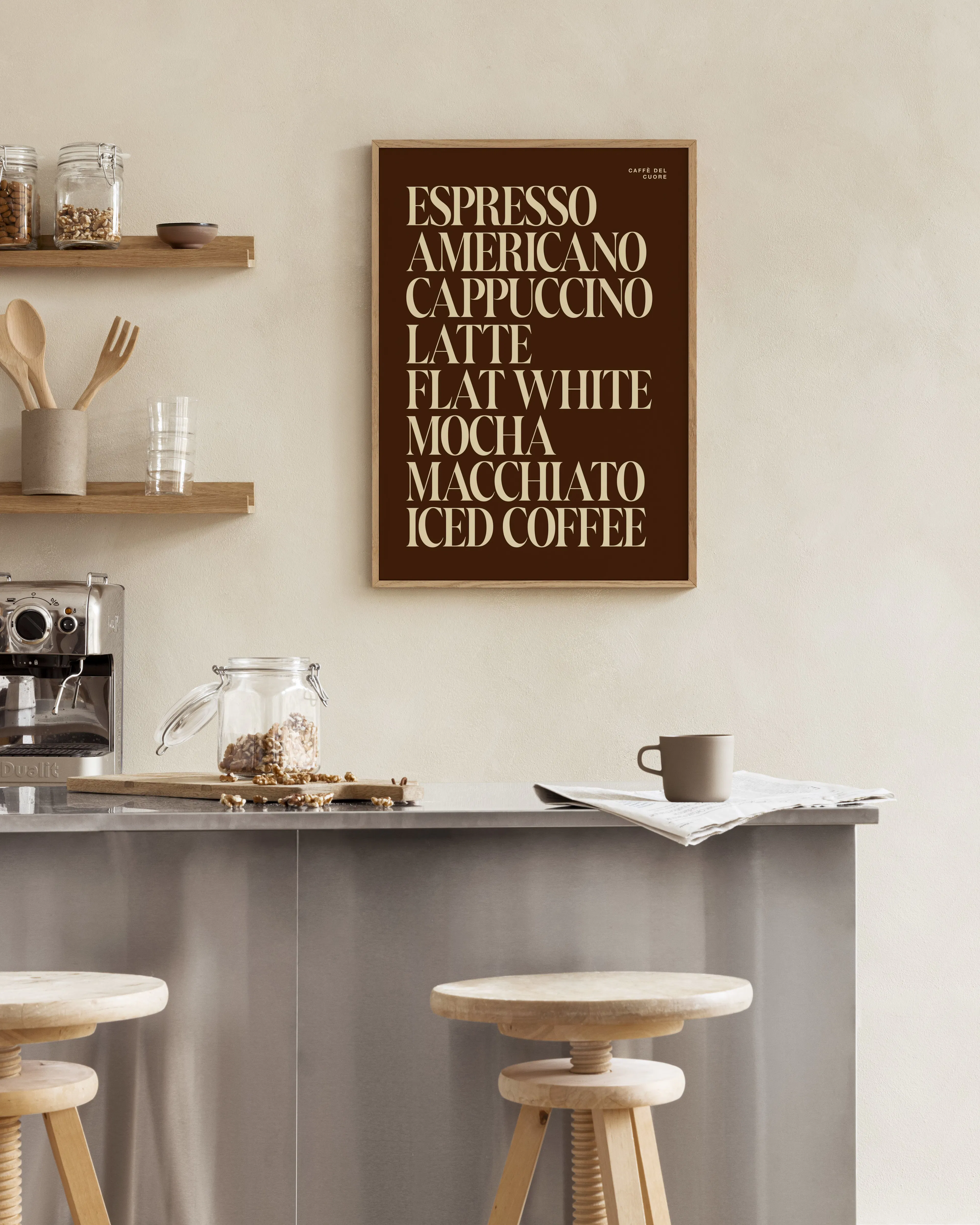 Coffee menu print with brown background and light beige text, hanging in a modern kitchen above a metal counter.