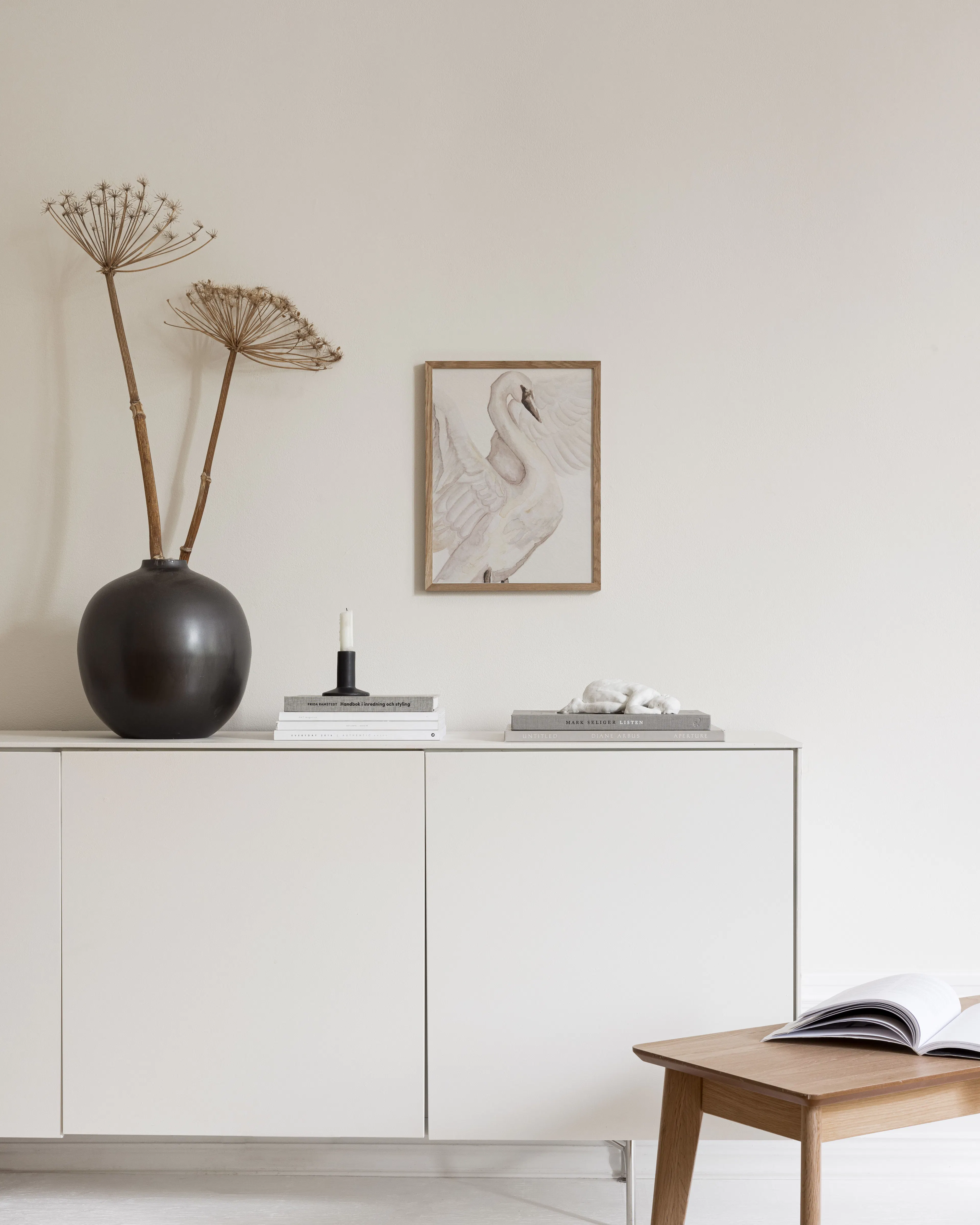 A print of a graceful white swan with outstretched wings on a light background, displayed on a cream fluffy rug in a modern room