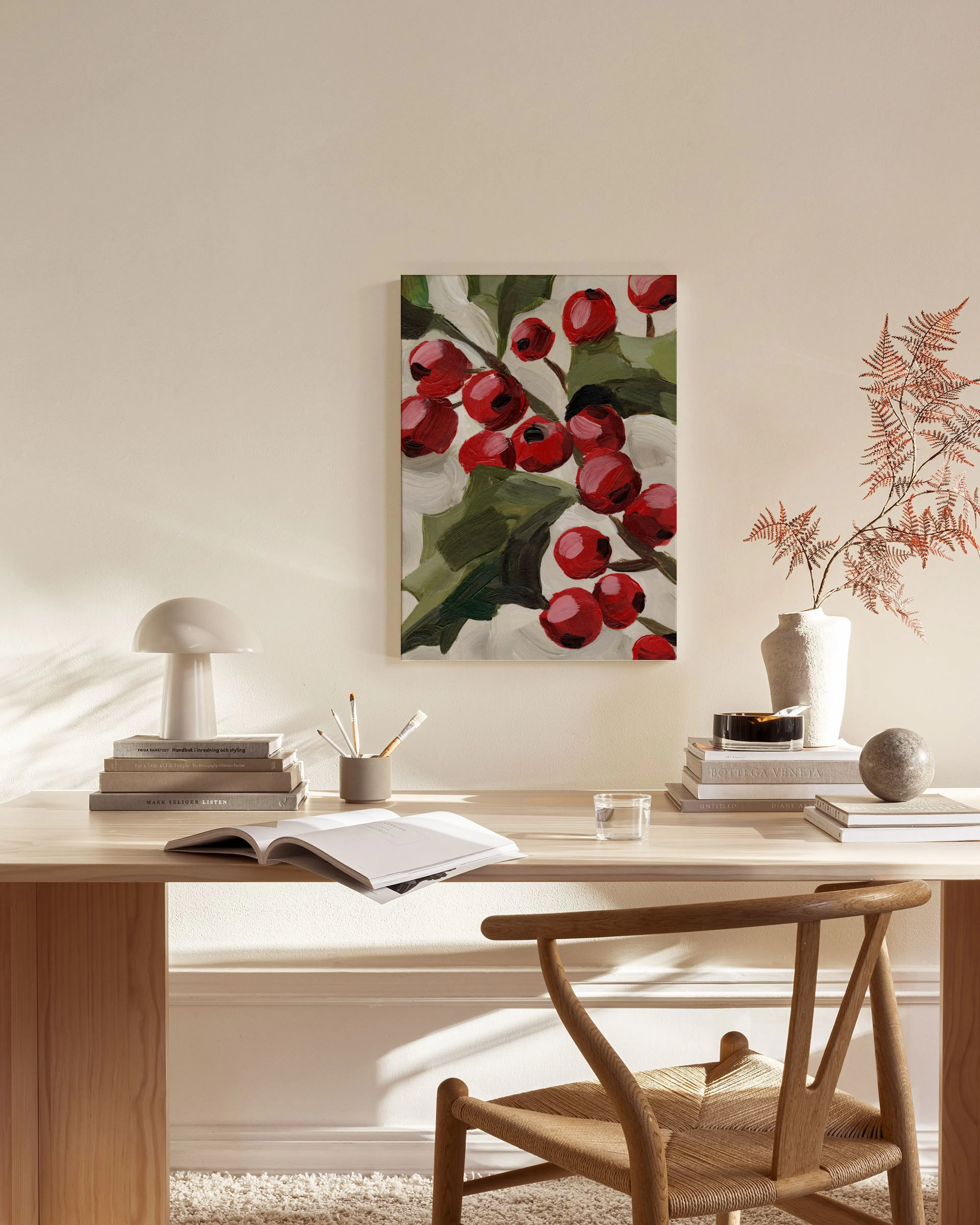 A canvas print of red berries and green leaves, with French text, hanging above a wooden console table in a living room.