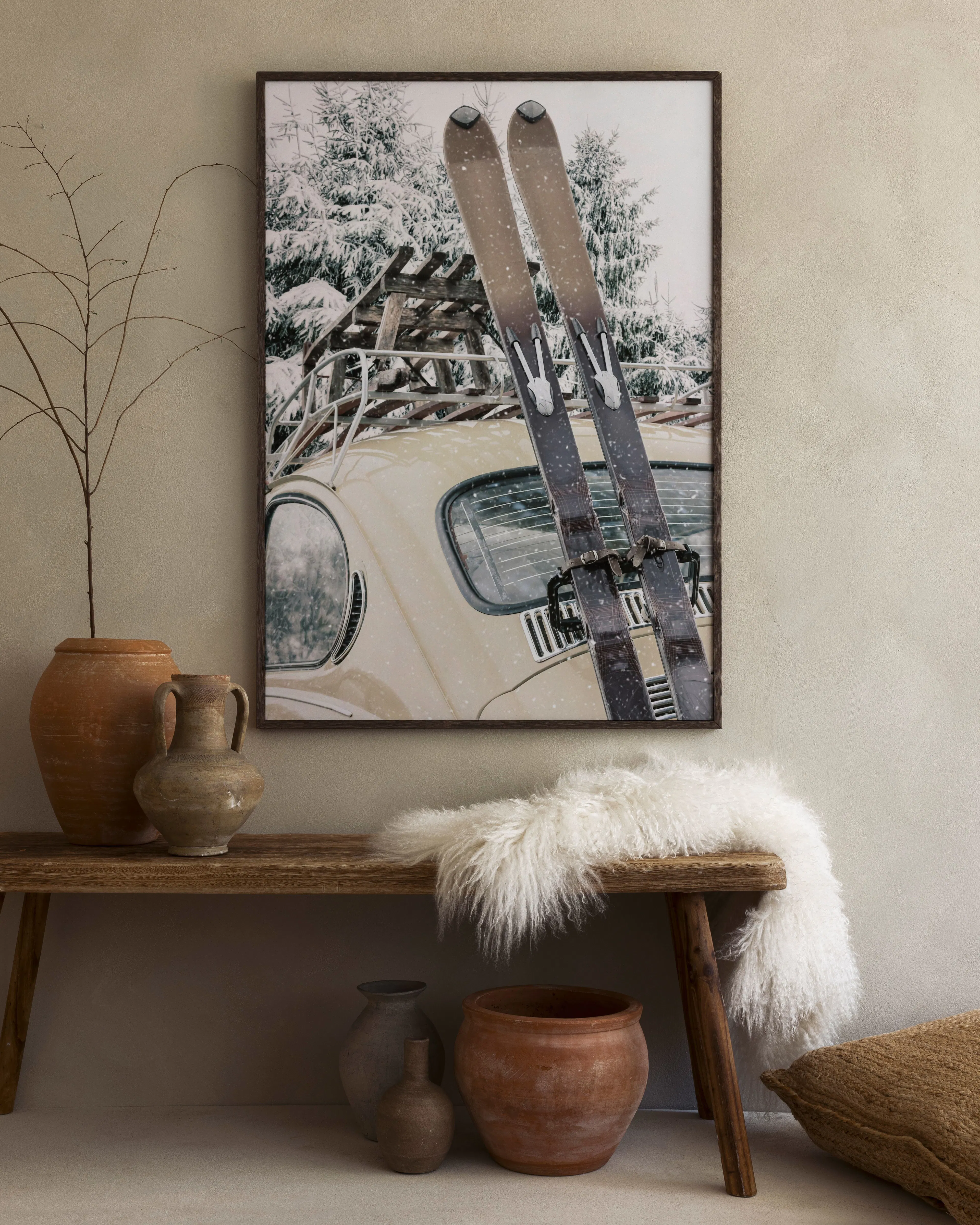 A print of skis on a car in a snowy forest, hanging above a rustic wooden bench with decorative pots.