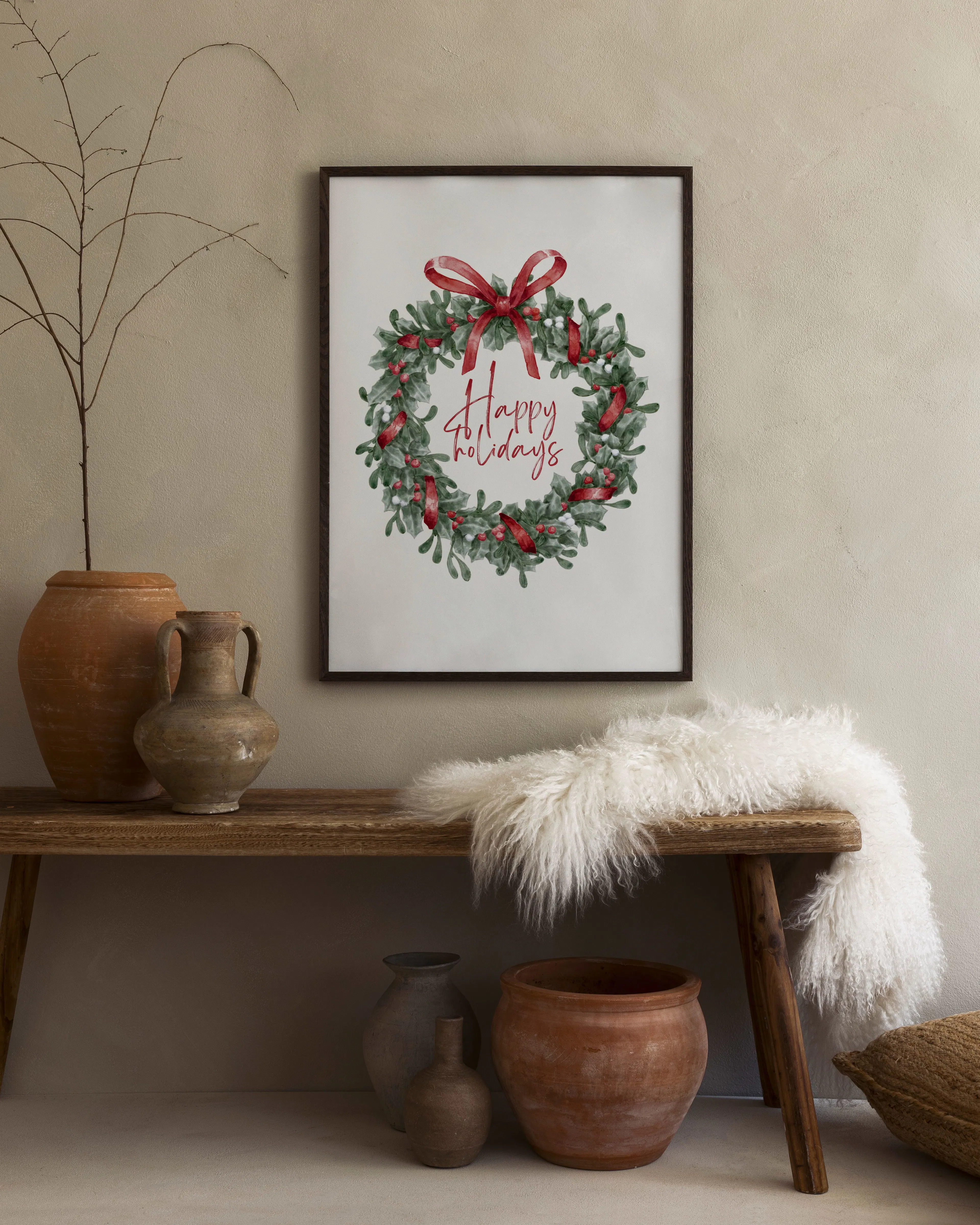 Affiche de Noël avec une couronne de houx et un ruban rouge, suspendue au-dessus dune vase blanche et de livres sur un tabouret.